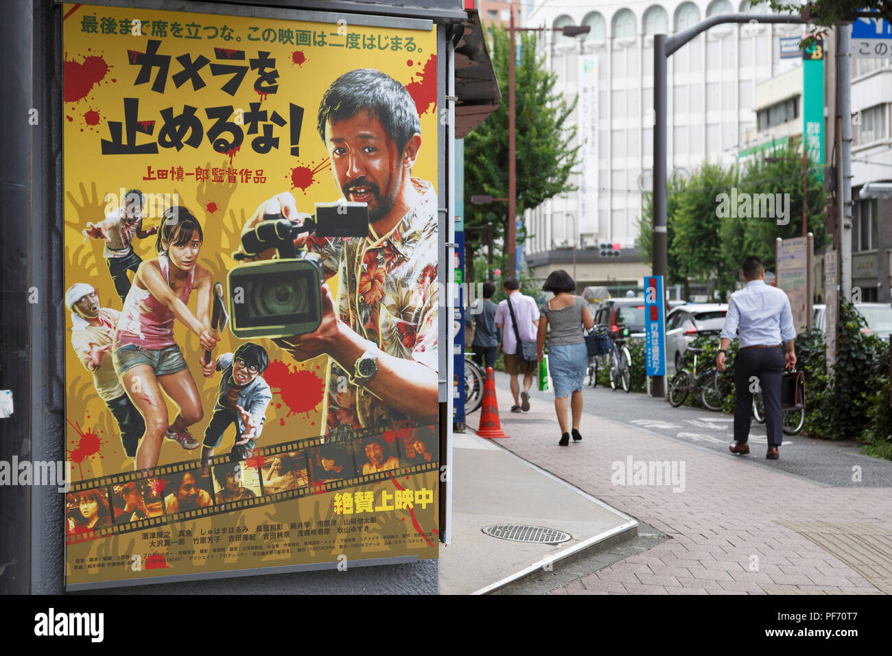 Les piétons passent devant une affiche du film une coupe des morts (titre japonais : Kamera o tomeru na !) sur l'affichage à l'extérieur de la salle de cinéma Cinéma Rosa le 20 août 2018, Tokyo, Japon. Le faible budget zombie comedy film directed by Shinichirou Ueda a reçu de bonnes réactions de la part des médias et des fans de films d'horreur. Credit : Rodrigo Reyes Marin/AFLO/Alamy Live News Banque D'Images