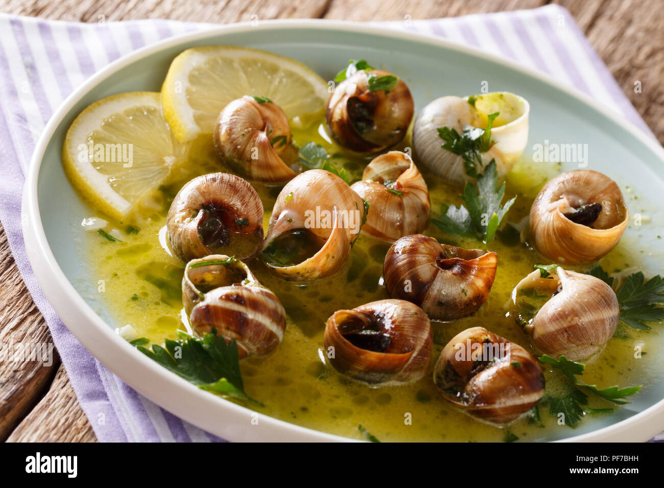 Escargots, escalgot au four avec du beurre, les herbes, le citron et l'ail  sur une plaque sur une table horizontale Photo Stock - Alamy