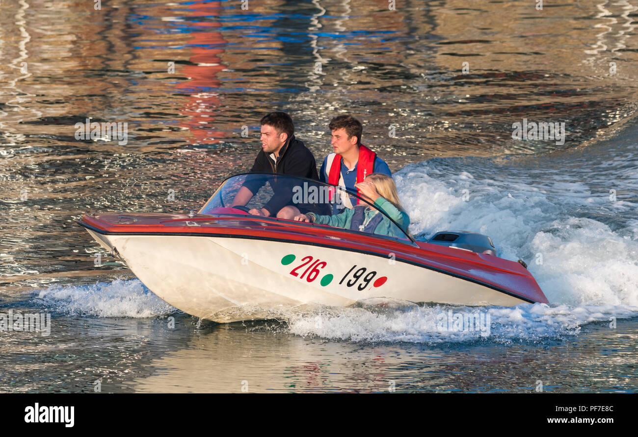Les jeunes gens en tenant une soirée en bateau sur la rivière Arun dans la belle lumière du soir au coucher du soleil, à Littlehampton, West Sussex, Angleterre, Royaume-Uni. Banque D'Images