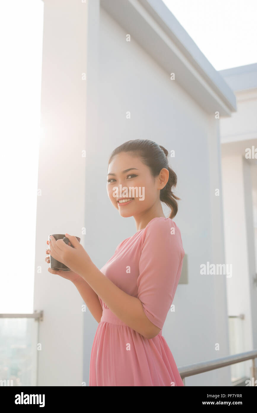 Young woman holding Coffee cup smiling at camera Banque D'Images