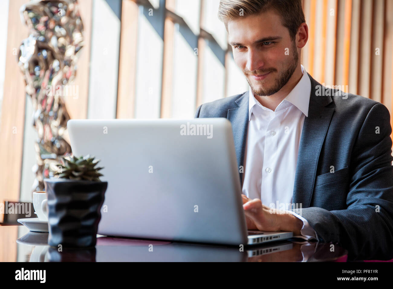Young businessman working on laptop, assis dans le hall de l'attente de quelqu'un. Banque D'Images