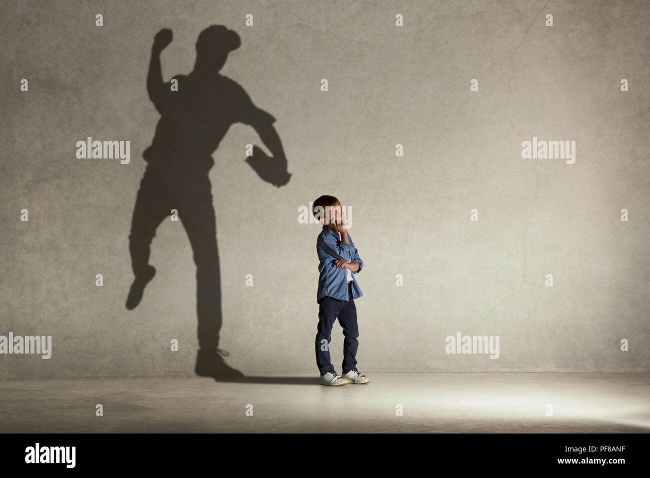 Champion de baseball américain. L'enfance et de l'dream concept. Image conceptuelle avec boy et ombre de monter sur le mur de l'athlète studio Banque D'Images