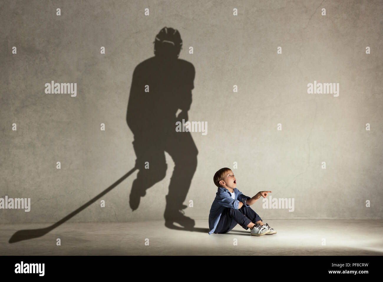 Champion de hockey sur glace. L'enfance et de l'dream concept. Image conceptuelle avec boy et ombre de monter sur le mur de l'athlète studio Banque D'Images