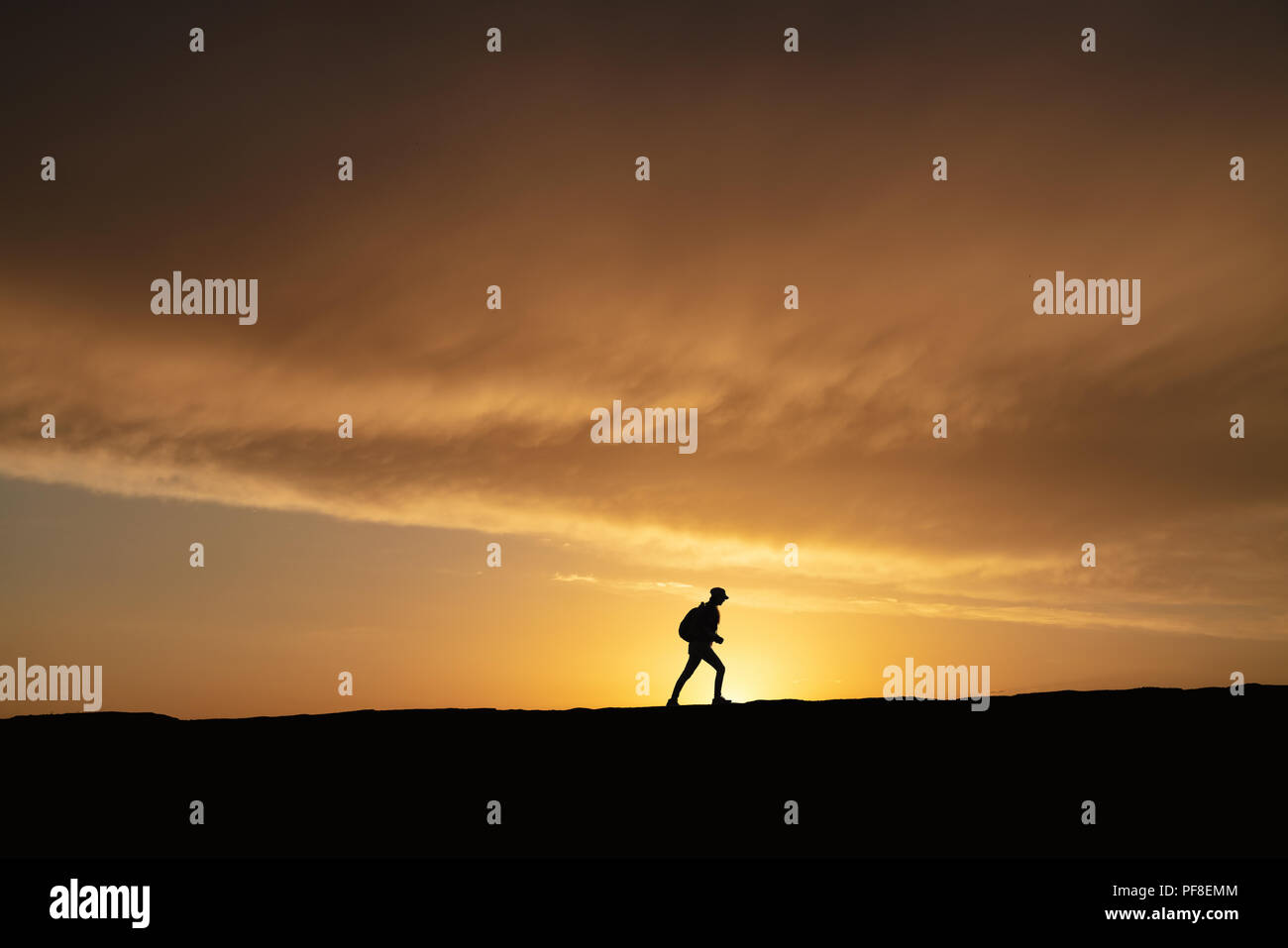 SIlhouette d'une femme seule balade au coucher du soleil sur une colline. Banque D'Images