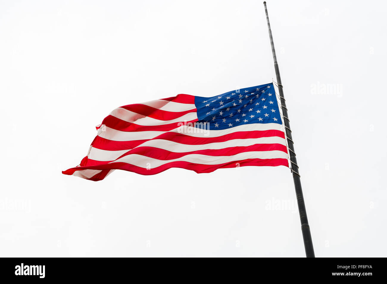 United States flag flying à demi-personnel forme contre ciel gris Banque D'Images