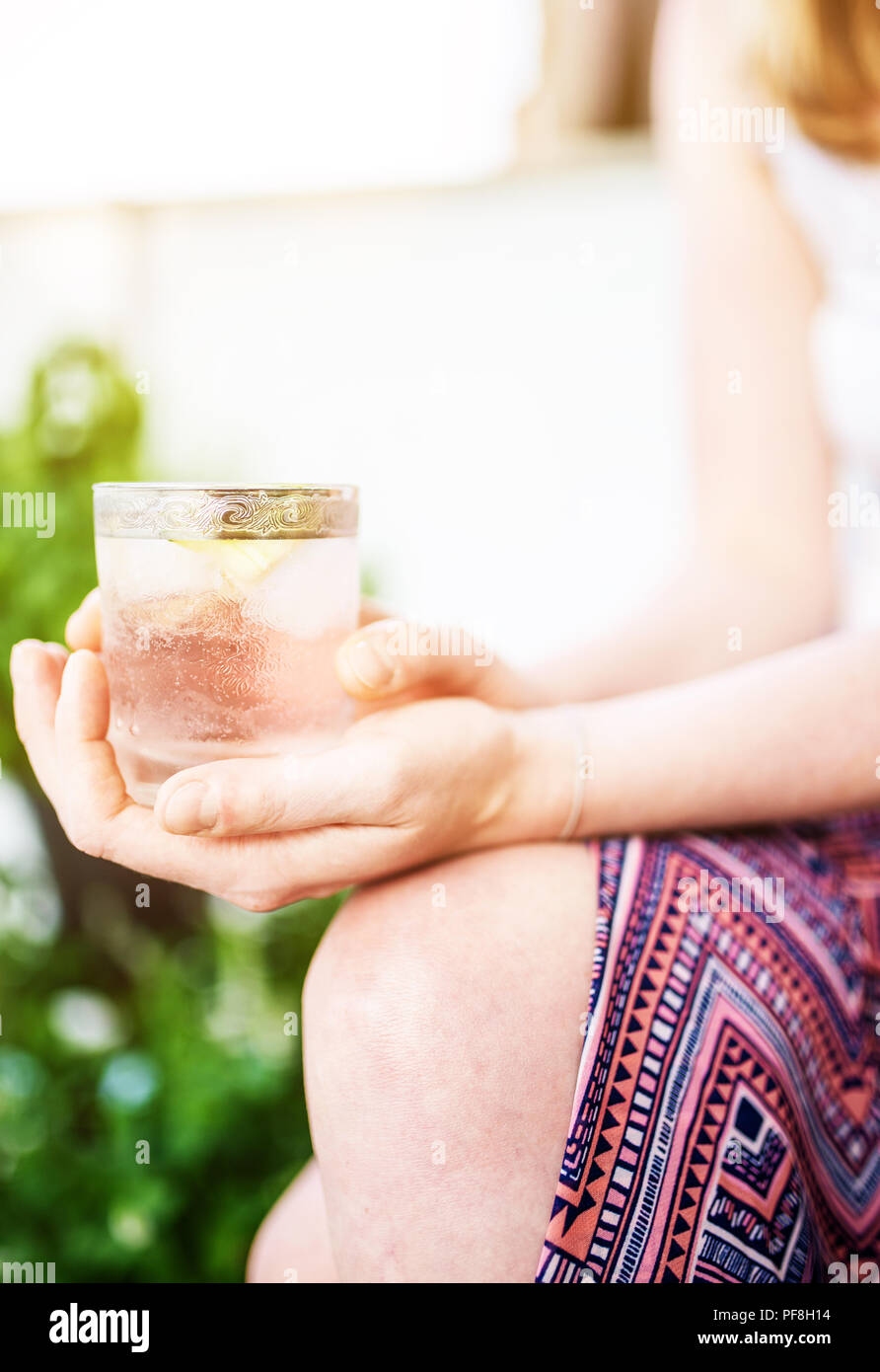 Blonde woman relaxing on patio holding boisson glacée Banque D'Images