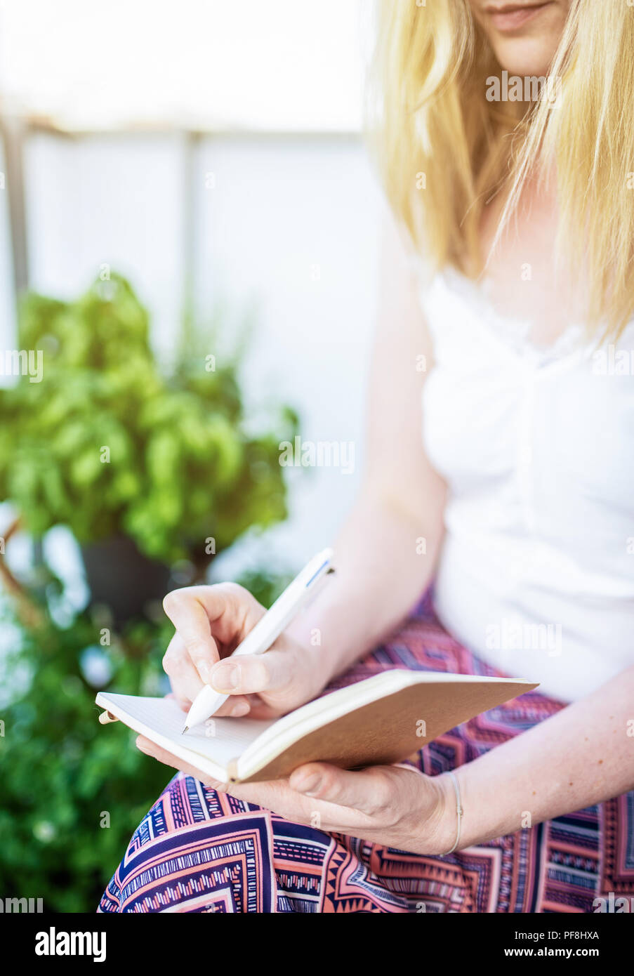 Close-up of woman sitting on patio en prenant des notes dans l'ordinateur portable Banque D'Images