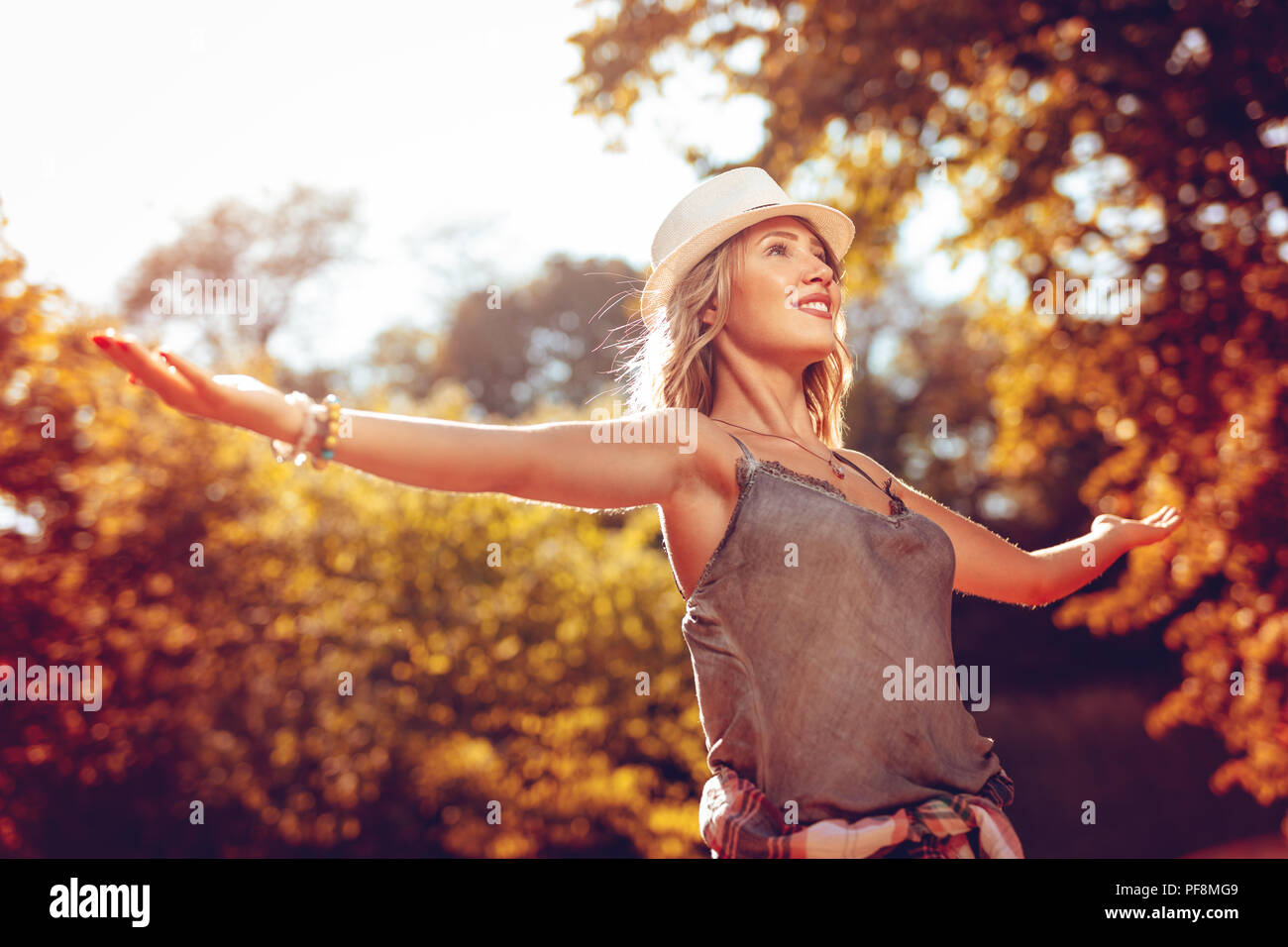 Happy young woman à bras ouverts dans la nature au début de l'automne journée ensoleillée. Banque D'Images