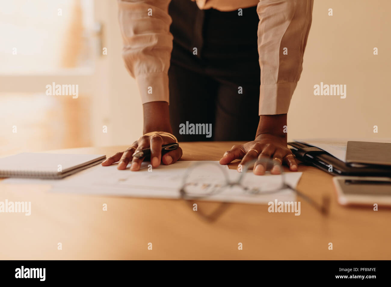 Close up de mains d'une femme entrepreneur tenir pen en appui sur la table. Businesswoman la lecture d'un document à la maison debout à côté d'une table tout en res Banque D'Images