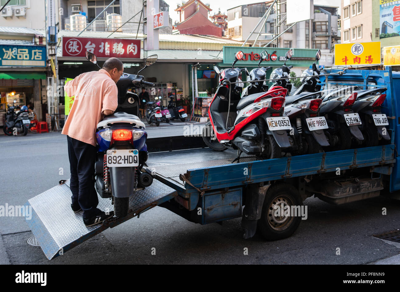 20 février 2018, Tainan, Taiwan : streetview de l'homme mettant un scooter dans un un camion plein de scooters en Tainan Taiwan Banque D'Images