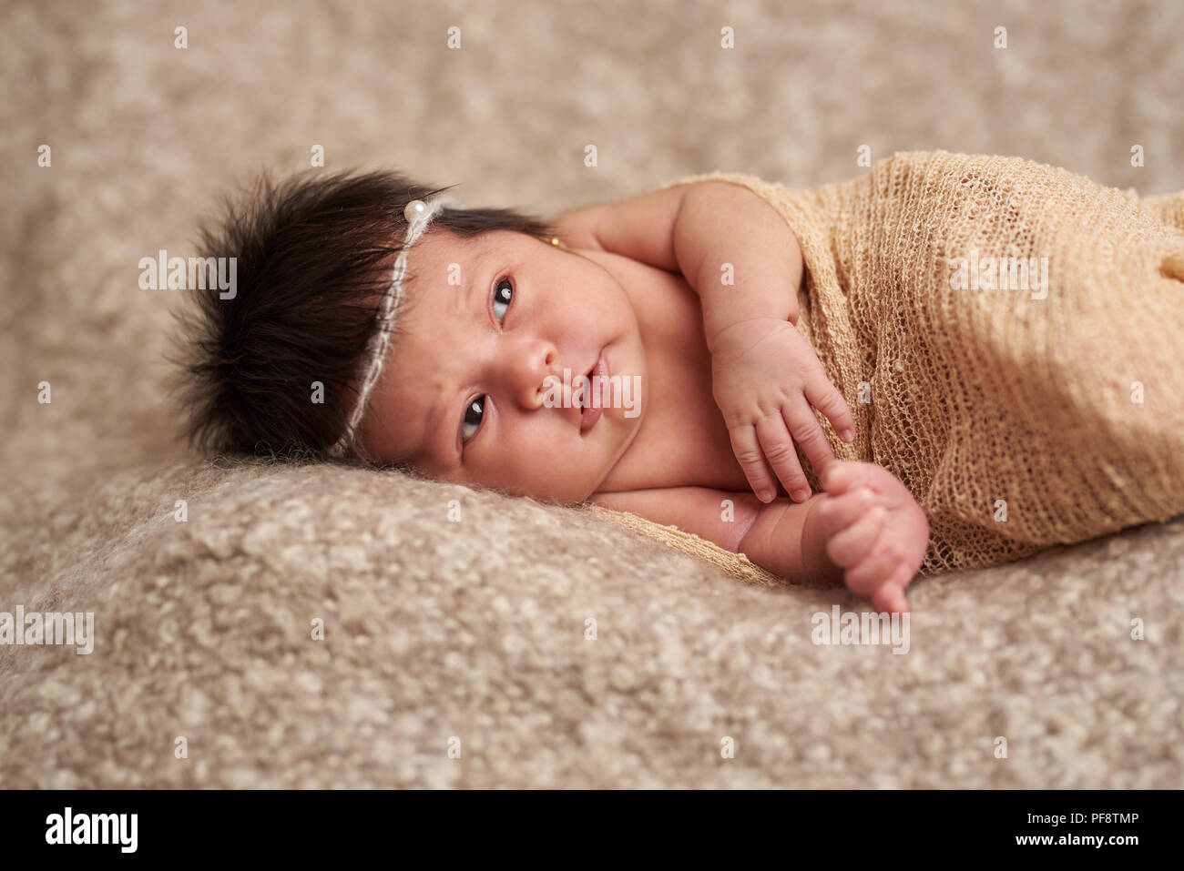Bébé nouveau-né à la recherche sur un fond brun retrouvez Banque D'Images