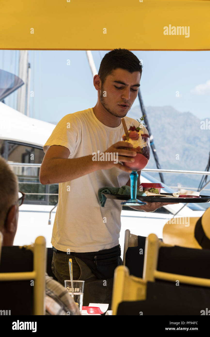 Un waiter serving une glace rempli de fruits tropicaux à un glacier à côté  du port de plaisance de Calvi en Corse, France Photo Stock - Alamy