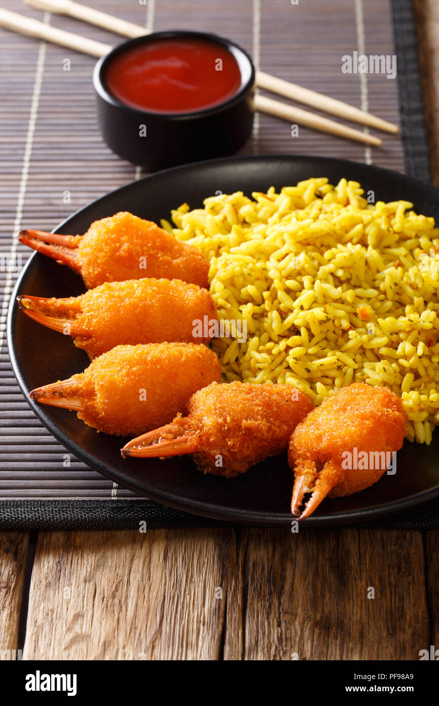 Fast food chinois pinces de crabe surimi dans la chapelure avec du riz jaune close-up sur une plaque sur une table verticale. Banque D'Images