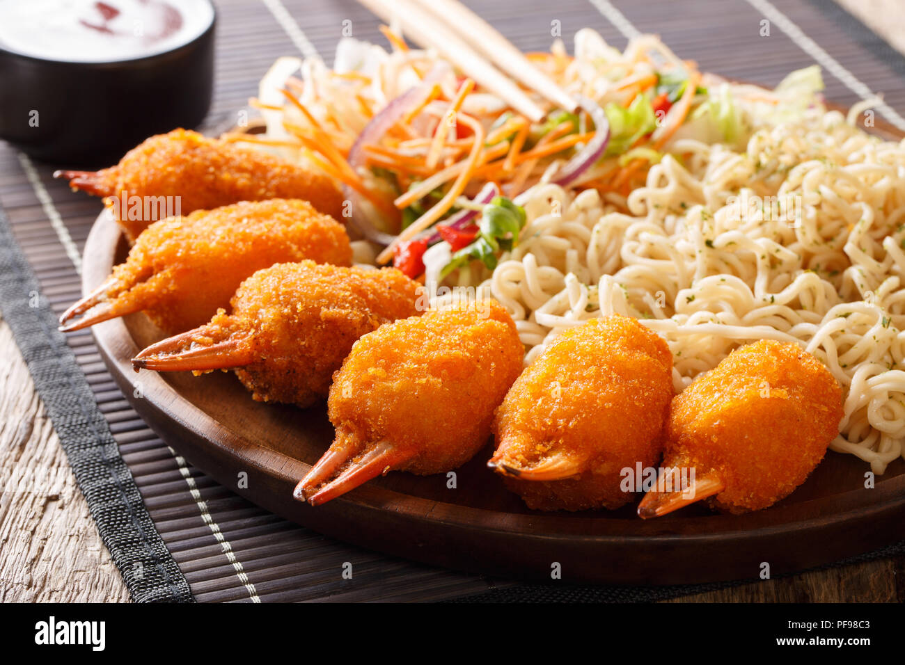 La cuisine chinoise : pinces de crabe dans la panure avec des nouilles aux œufs et une salade de légumes frais close-up sur une plaque sur une table horizontale. Banque D'Images