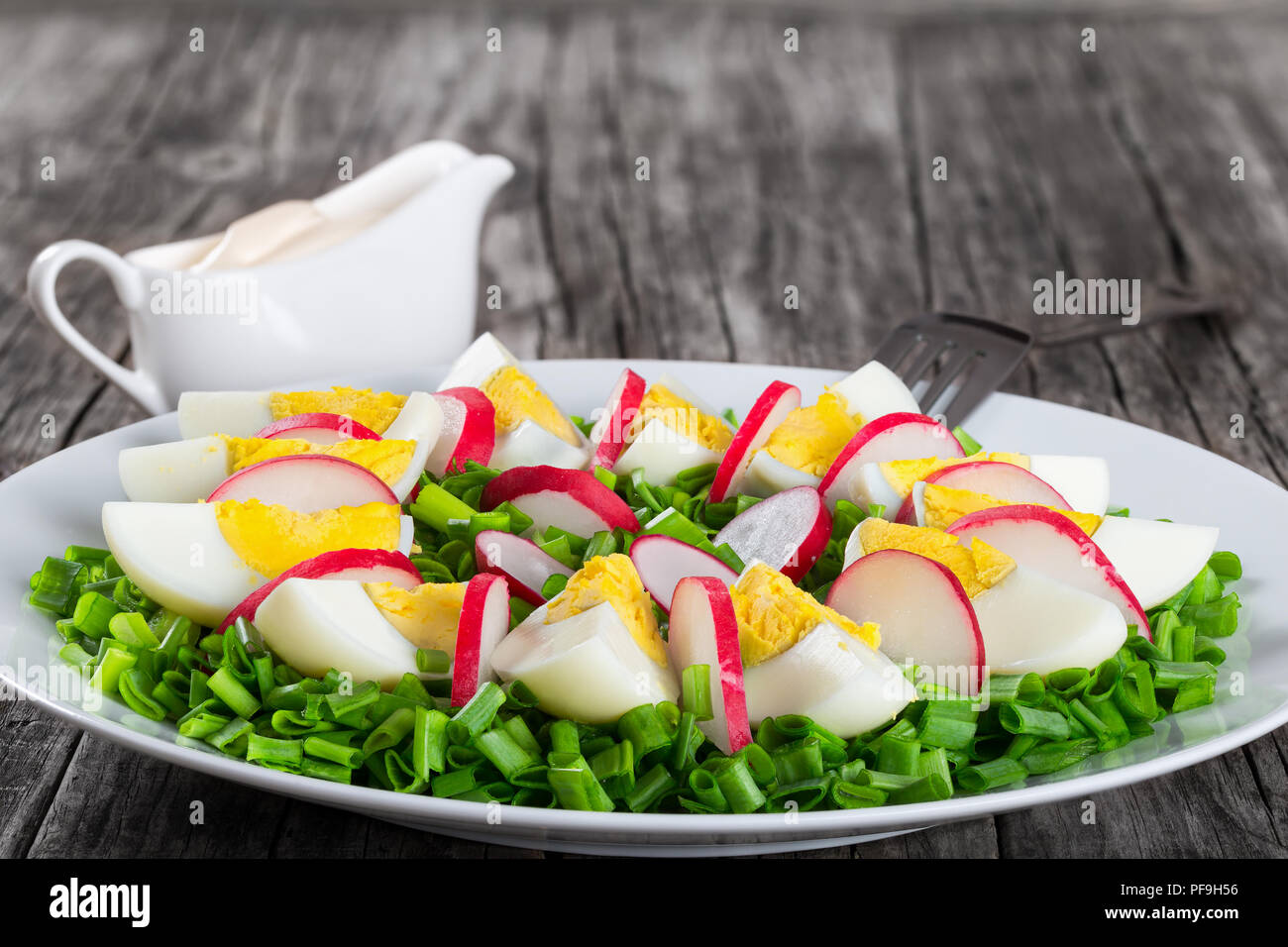De délicieux petits oignons, oeufs, salade de radis blanc dans un plat d'une fourchette sur une vieille table rustique, simple et facile recette, close-up horizontale Banque D'Images