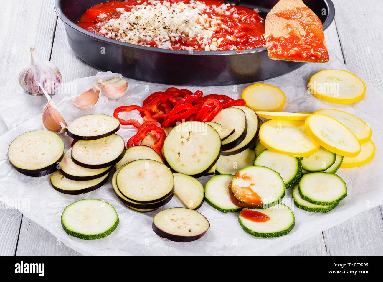 Ingrédients de base pour une cuisine française en cocotte, ratatouille :  courgette, poivron rouge, oignon, courgettes jaunes, aubergines, sauce  tomate et l'ail sur un Photo Stock - Alamy