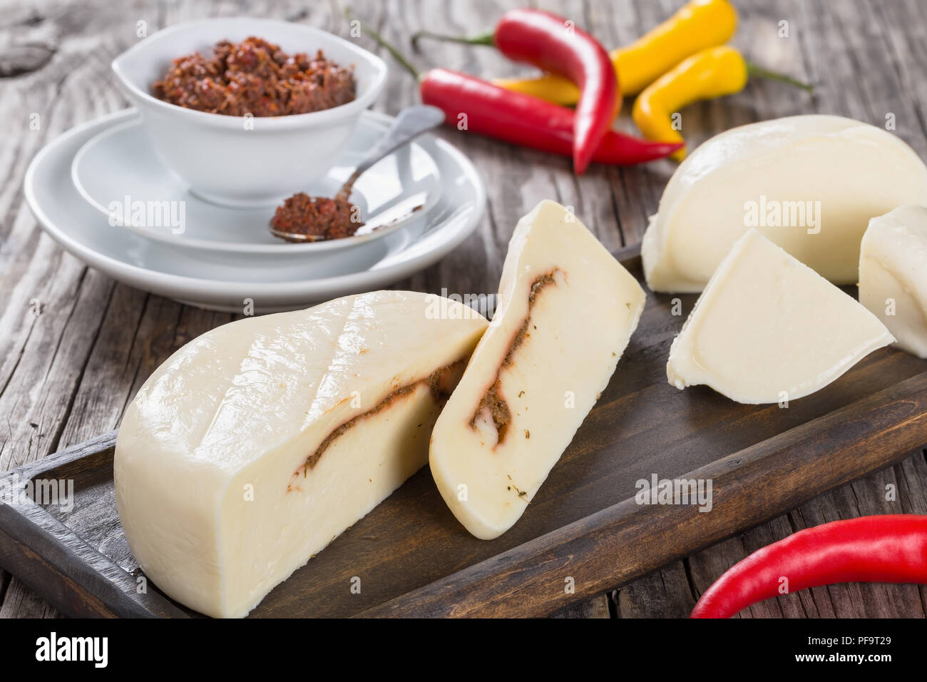 La mozzarella maison remplir hermétiquement avec adjika ou pesto rouge, chaud, épicé mais subtilement parfumé, dip sur plateau en bois foncé, avec du chili sur background, close-up Banque D'Images