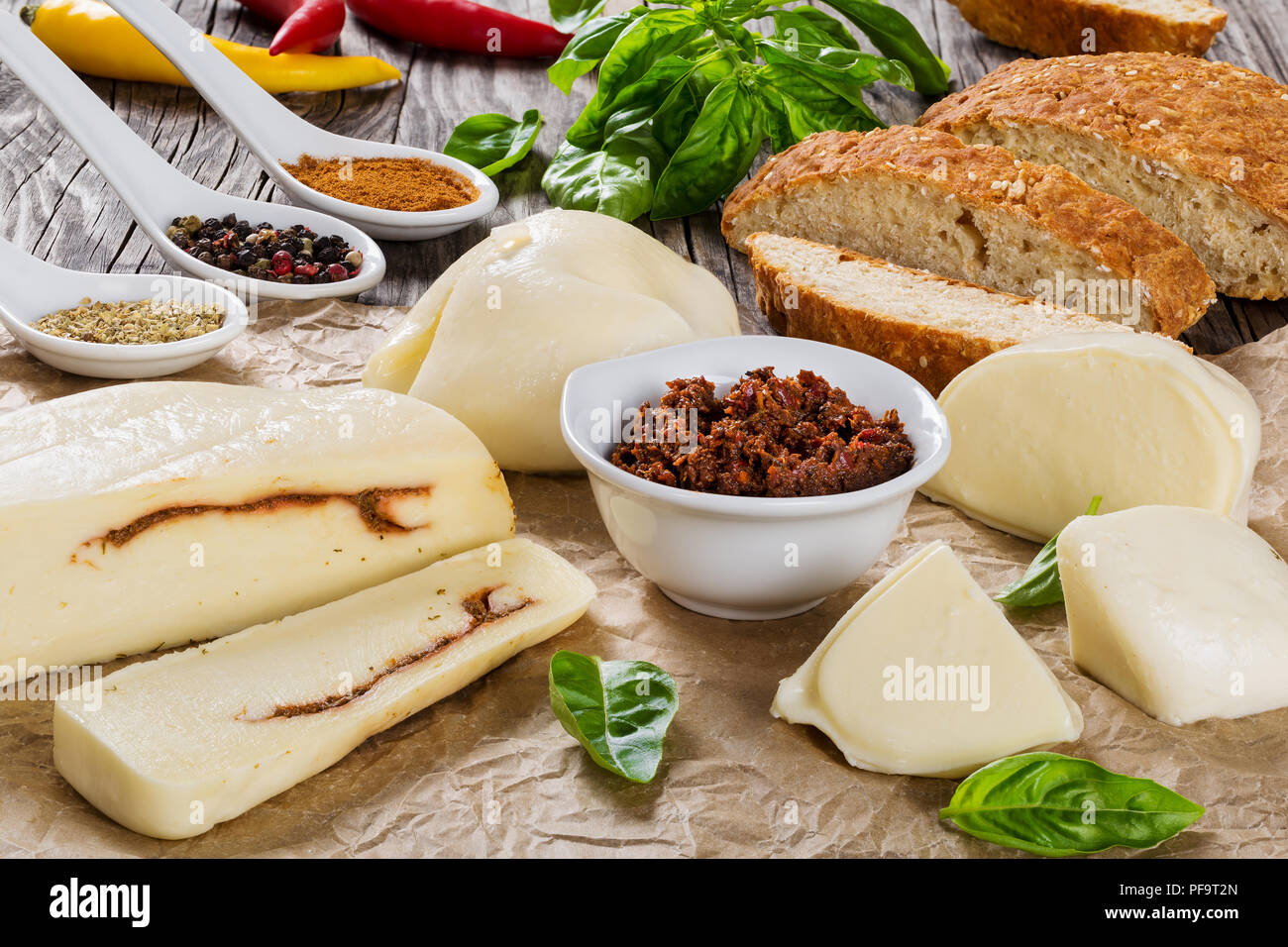 La mozzarella maison remplir hermétiquement avec adjika ou pesto rouge, chaud et épicé sur le papier parchemin, avec du chili, tranches de pain à grains entiers, le basilic et les épices Banque D'Images