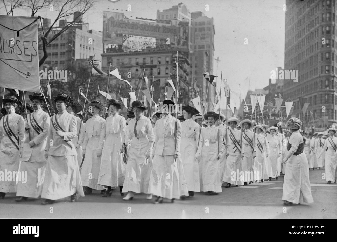 Photographie noir et blanc montrant un groupe d'infirmières, vêtus de blanc, et les ceintures vêtements édouardienne lire 'le vote des femmes, ' et fanions holding, tout en démontrant à New York en 1913. () Banque D'Images