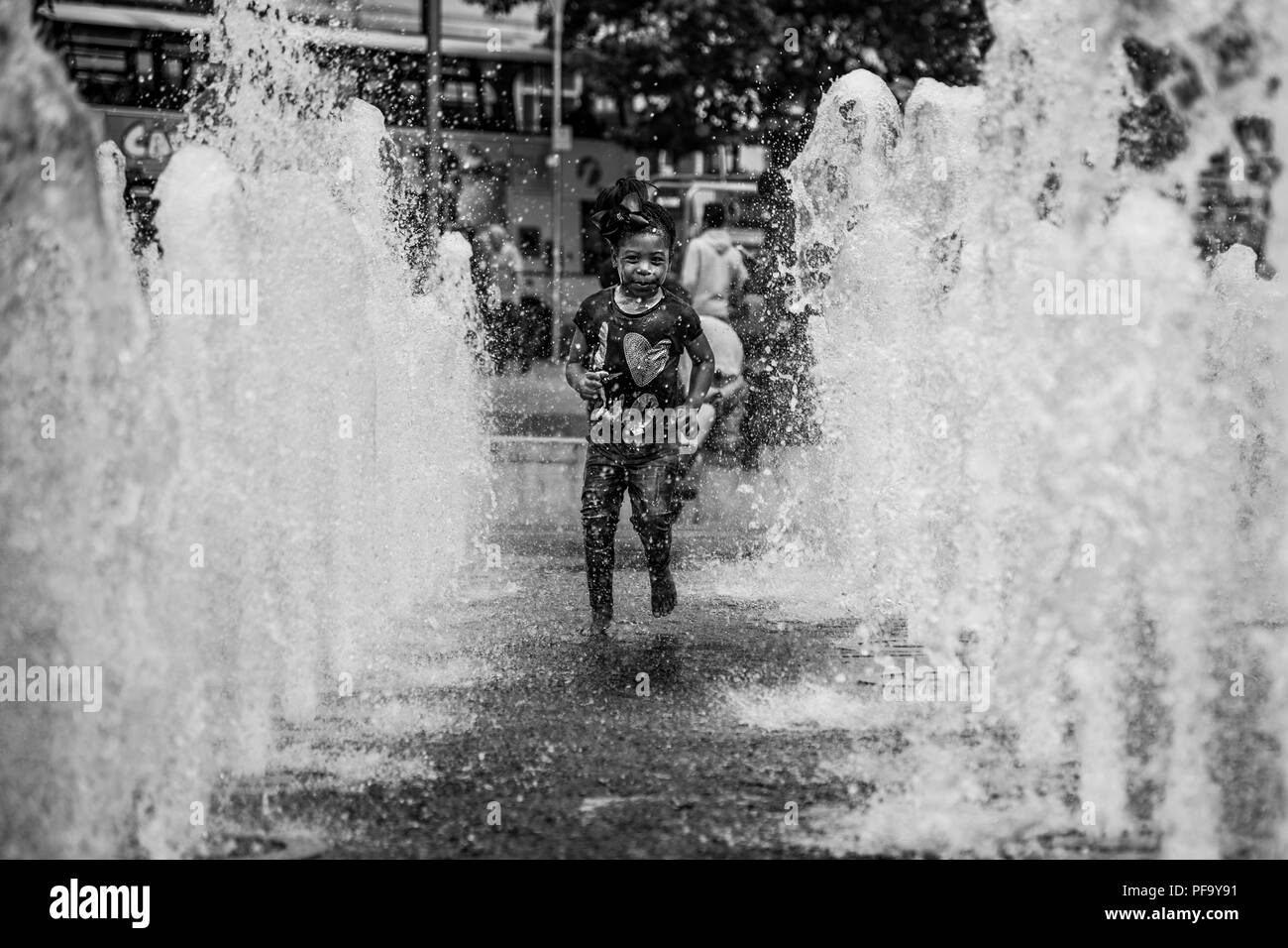 Fille joue dans l'eau des fontaines dans Piccadilly Gardens dans le centre-ville de Manchester, Royaume-Uni Banque D'Images