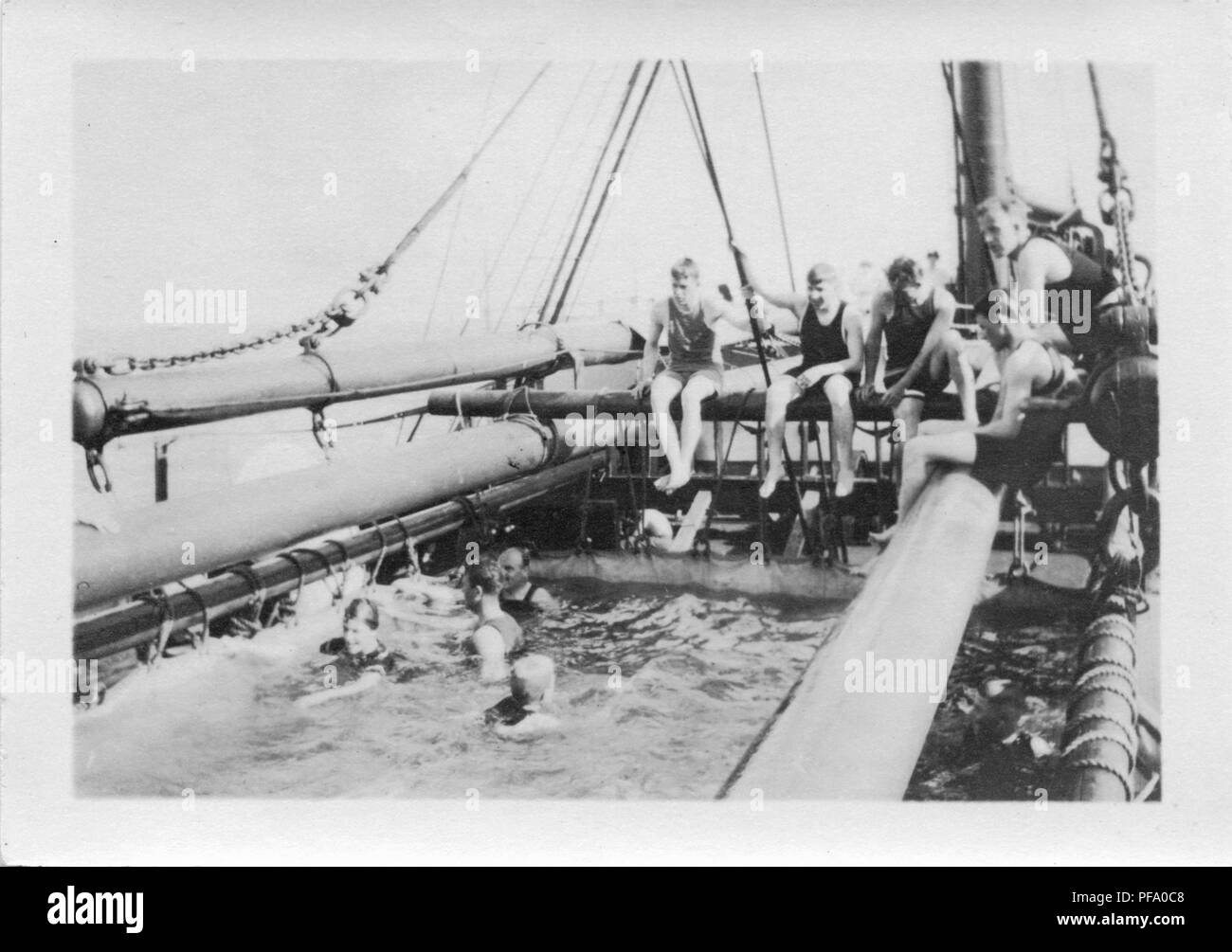 Photographie noir et blanc, montrant les hommes assis et s'appuyant sur le gréement, et nager dans une grande toile extérieure, enfilés sur le pont d'un navire qui navigue le Canal de Panama, 1915. () Banque D'Images