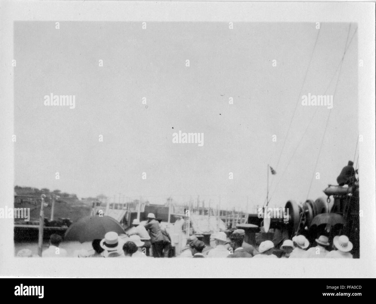 Photographie noir et blanc, tourné à partir d'un angle élevé, montrant un groupe de personnes, beaucoup de porter un chapeau, puisqu'elles se tiennent sur le pont d'un navire qui quitte un blocage du canal de Panama, avec des poteaux d'éclairage électrique et les voies de chemin de fer visible sur le canal des banques de la distance, 1915. () Banque D'Images