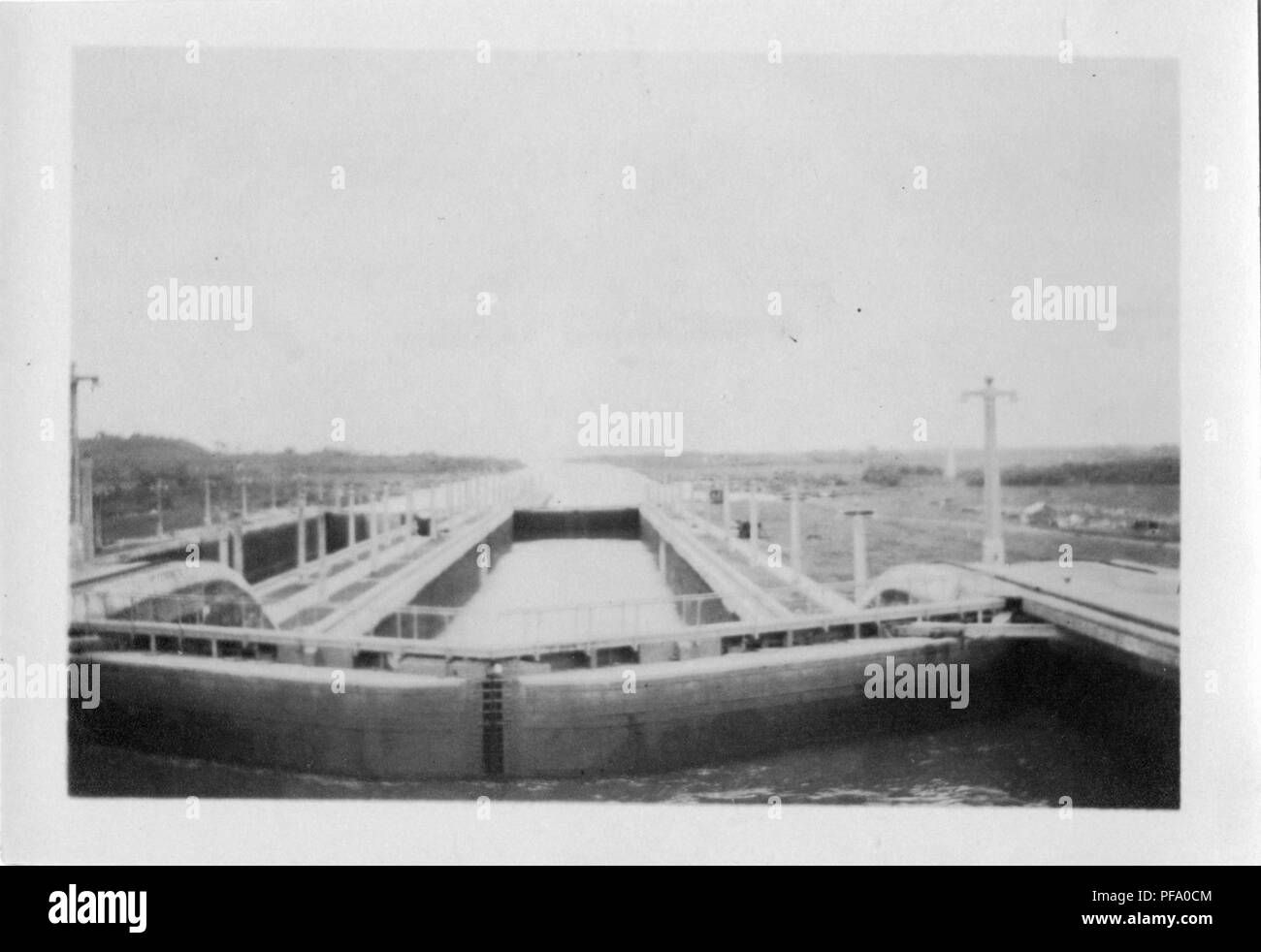 Photographie noir et blanc, tourné à partir d'un angle élevé, probablement le pont d'un navire, montrant le bras d'une écluse du canal de Panama, avec des rails de chemin de fer et poteaux électriques de lumière visible sur les bords de chaque côté, 1915. () Banque D'Images