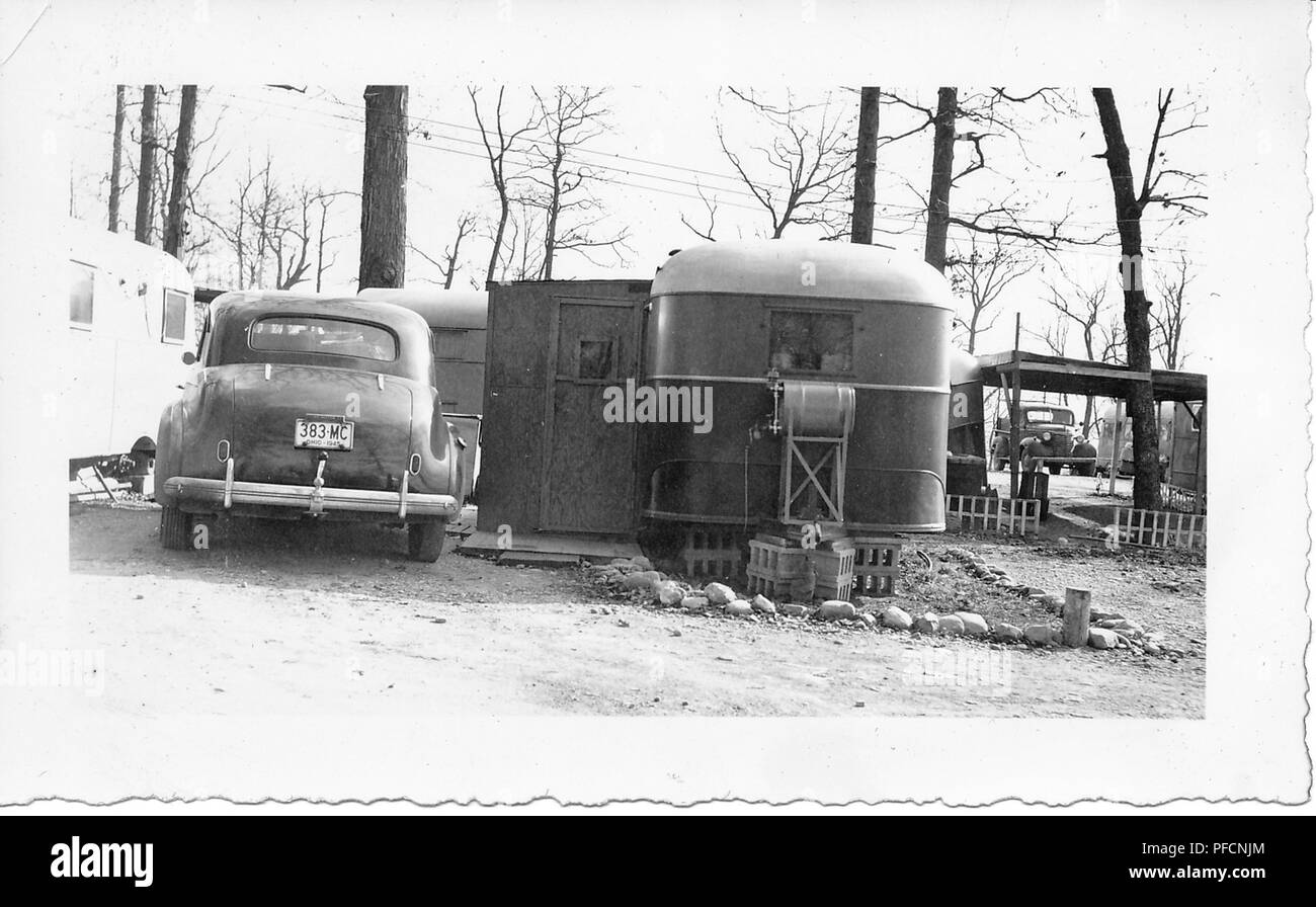 Photographie noir et blanc, montrant l'arrière d'une voiture Chevrolet Sedan vintage, avec une plaque d'immatriculation de l'Ohio en date du 1945, stationné à l'extérieur, dans un paysage hiver, à côté d'un couple de caravanes ou remorques tractées, probablement photographié en Ohio dans la décennie suivant la Seconde Guerre mondiale, 1950. () Banque D'Images