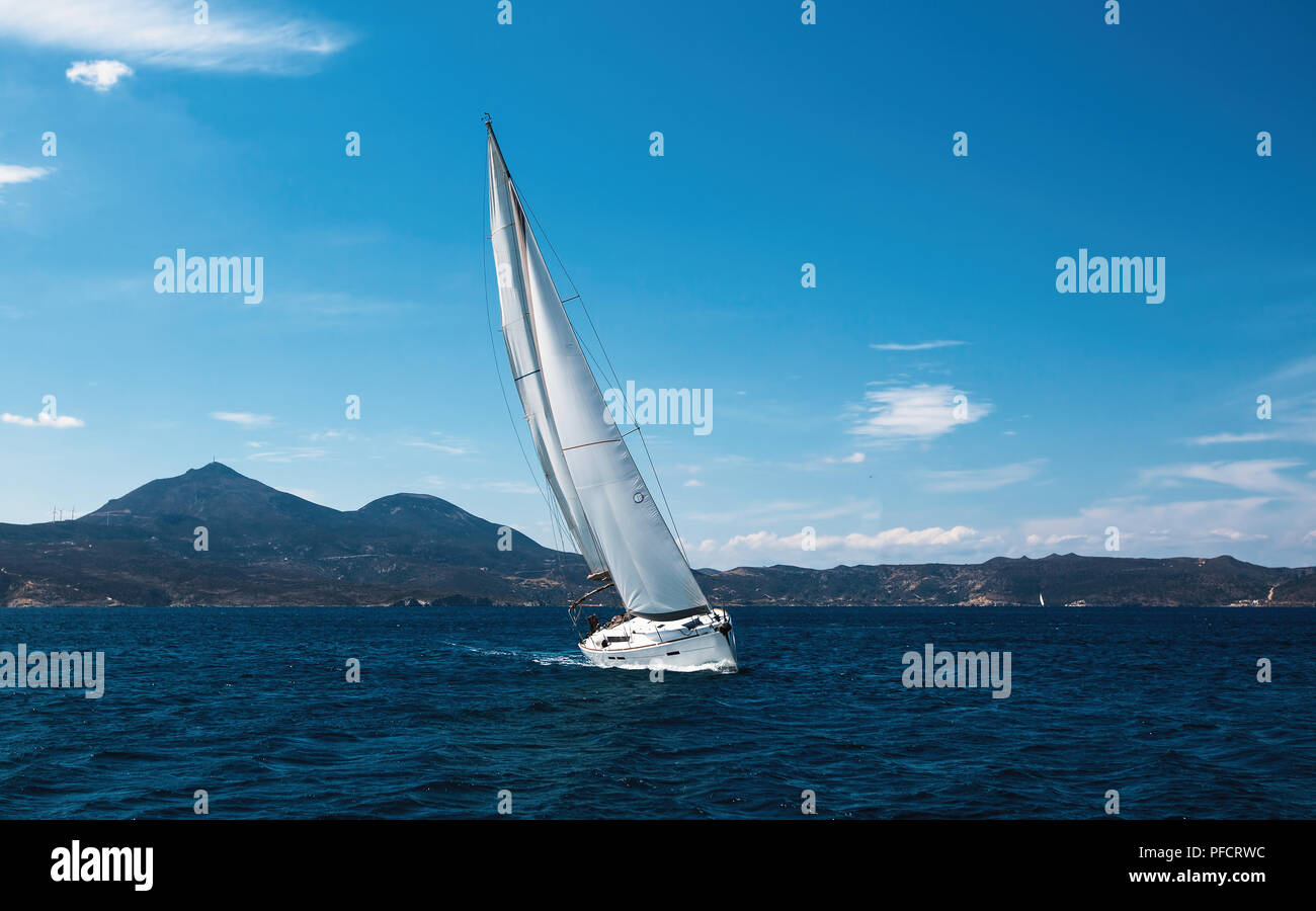Bateau à bateau yacht à voiles blanches se glisse à travers les vagues dans la mer. Banque D'Images