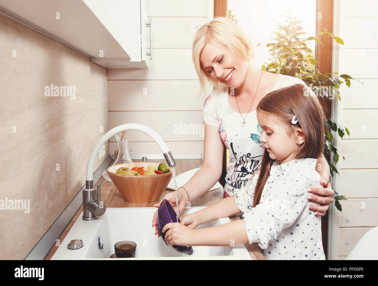 Belle blonde mère et fille cute brunette peu laver la vaisselle sur la cuisine légère Banque D'Images