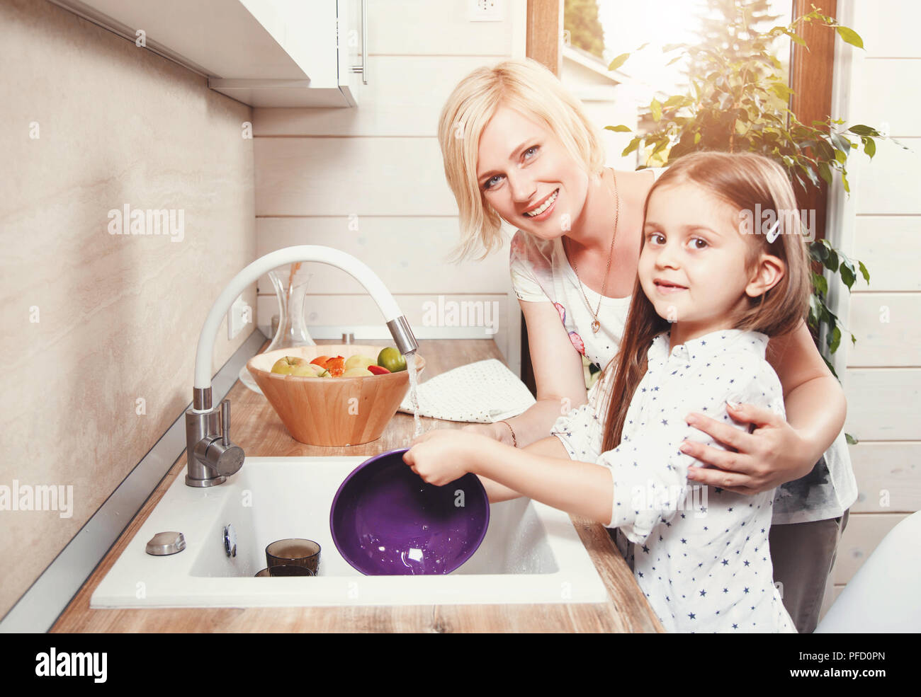Belle blonde mère et fille cute brunette peu laver la vaisselle sur la cuisine légère, le soutien de la famille concept Banque D'Images