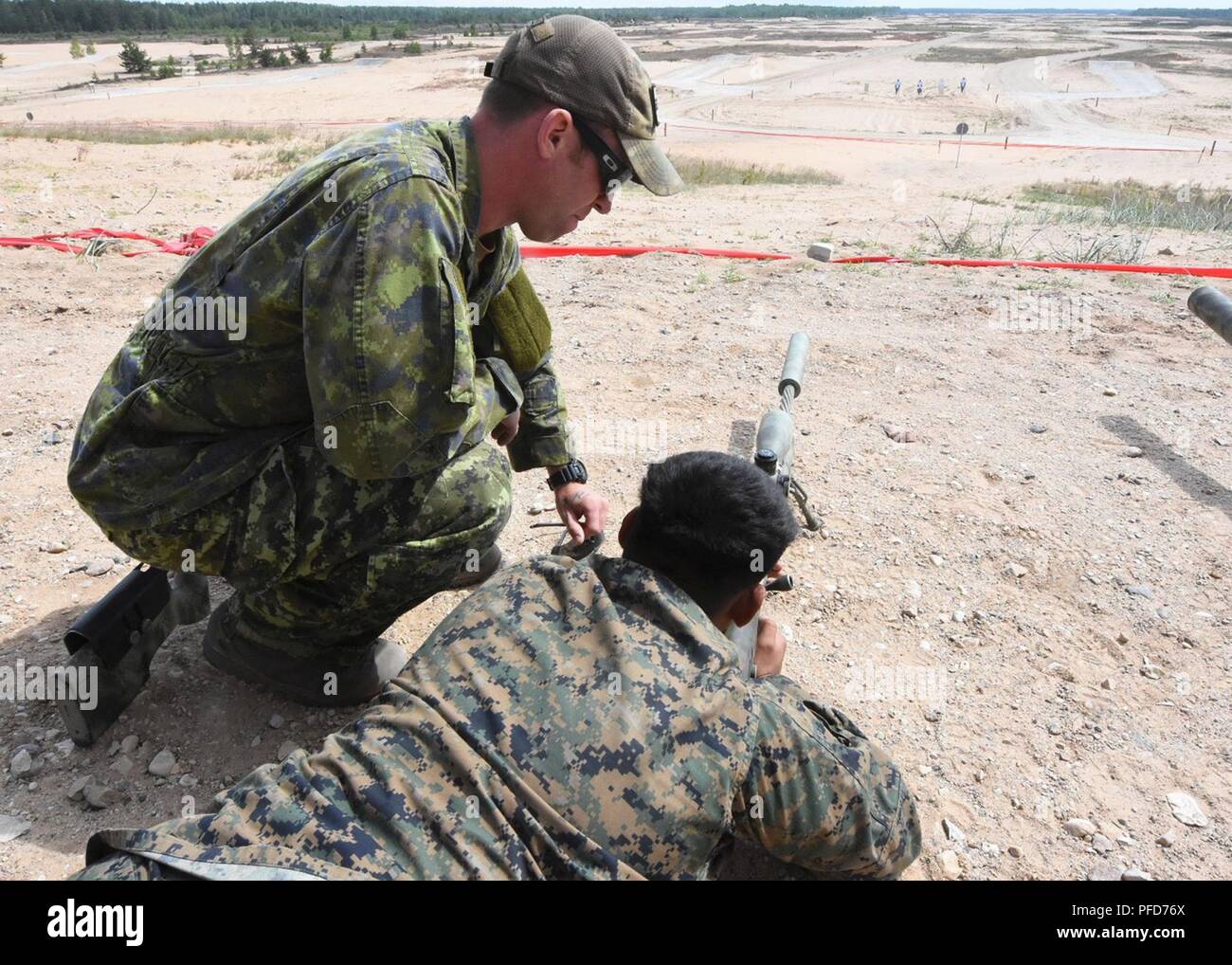 Un soldat canadien de la 2e Bataillon, Royal Canadian Regiment forme l'Armée Lance Cpl. Alvaro Gonzales de la Compagnie Bravo, 4e bataillon de chars, Yakima, WA., sur la McMillan TAC-50- long-range, fusil de tireur de précision pour l'exercice de la grève 18 Sabre à Adazi, base de la Lettonie le 8 juin 2018. Cet exercice est la huitième édition de l'armée américaine de longue date par l'Europe de la formation coopérative exercice visant à accroître l'interopérabilité entre les alliés et les partenaires régionaux Banque D'Images