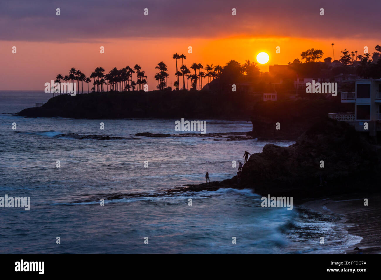 Belle vue sur la côte d'un ciel coloré au coucher du soleil avec des vagues se briser dans des formations rocheuses et silhouette de palmiers, les plongeurs Cove, Laguna Beach, C Banque D'Images