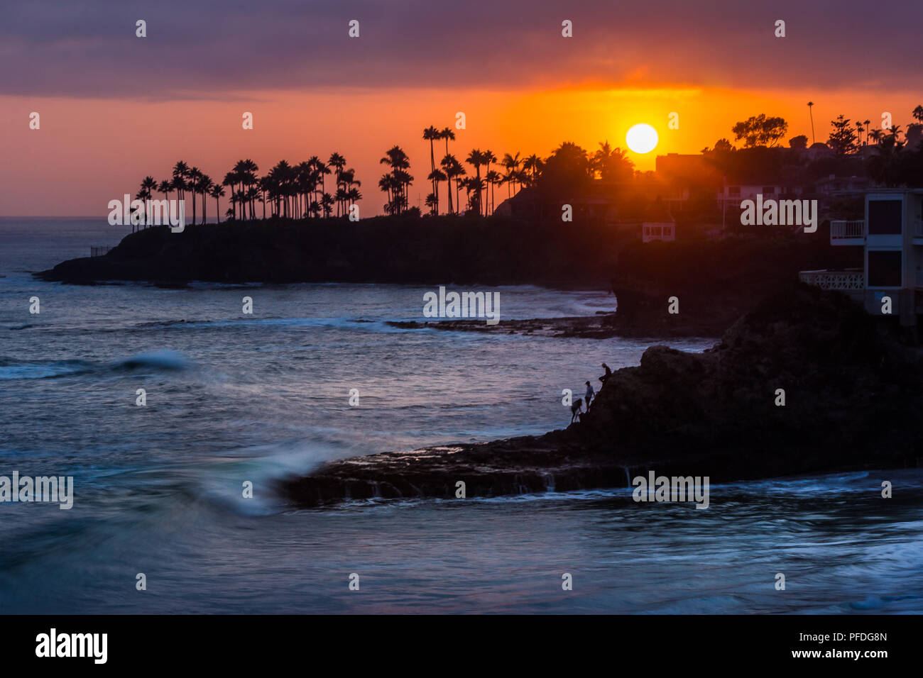 Belle vue sur la côte d'un ciel coloré au coucher du soleil avec des vagues se briser dans des formations rocheuses et silhouette de palmiers, les plongeurs Cove, Laguna Beach, C Banque D'Images