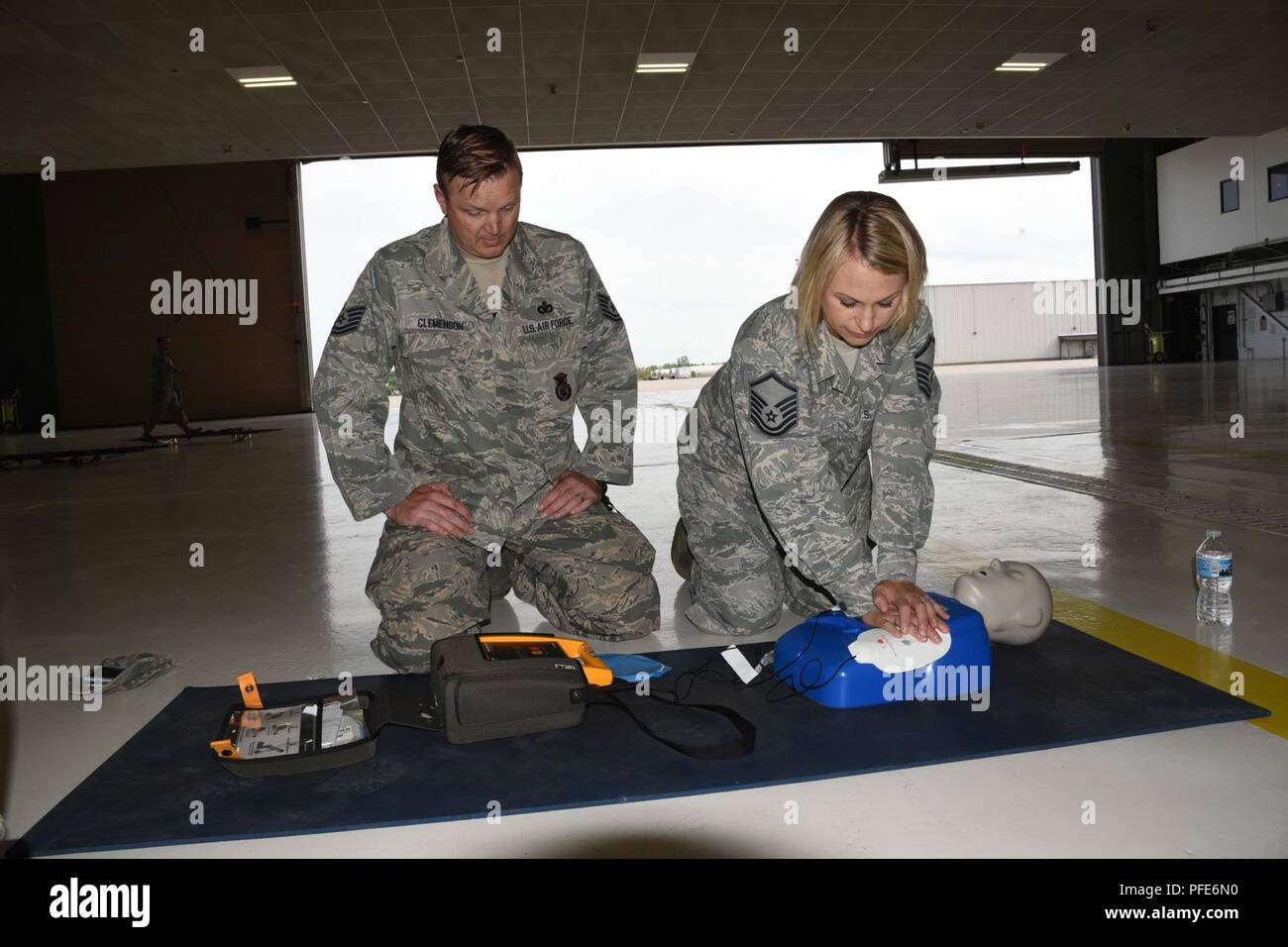 Le sergent-chef de l'US Air Force. Tina Sly, du 119e Escadron de soutien de la Force, droit, pratiques réanimation cardio pulmonaire (RCP) le massage cardiaque sur un mannequin de formation de Tech. Le Sgt. Erik Clemenson, du 119e Escadron des Forces de sécurité, surveille la charge électronique d'un défibrillateur automatisé externe au cours de l'auto-aide et soins buddy (SABC) Formation à la North Dakota Air National Guard Base, Fargo, N.D., 8 juin 2018. SABC est pratiquée de façon à ce que les aviateurs peuvent fournir des soins médicaux pour les uns les autres dans des situations d'urgence, lorsque les soins professionnels n'est pas facilement disponible. Les exigences de la formation Banque D'Images