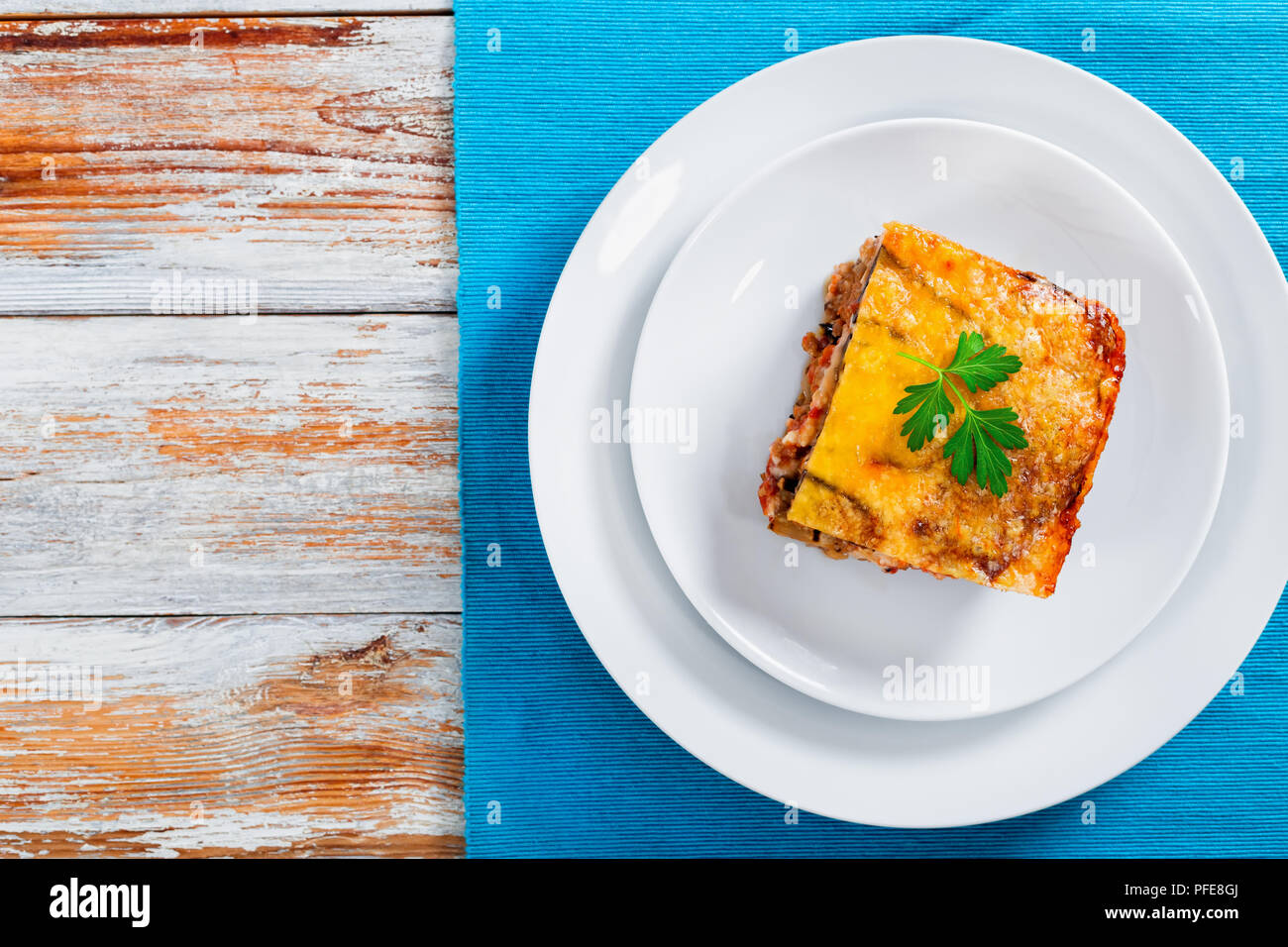 Partie de la moussaka délicieux décoré de persil cuit pour recette authentique, sur les plaques sur tapis de table, sur les conseils de la peinture blanche, vue depuis l'ab Banque D'Images