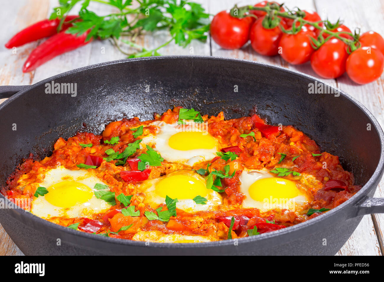 Délicieux moyen-orient shakshuka - œufs frits, oignon, poivron, tomate, piment et épices dans vieux poêle en fonte sur fond de bois, classic destinat Banque D'Images