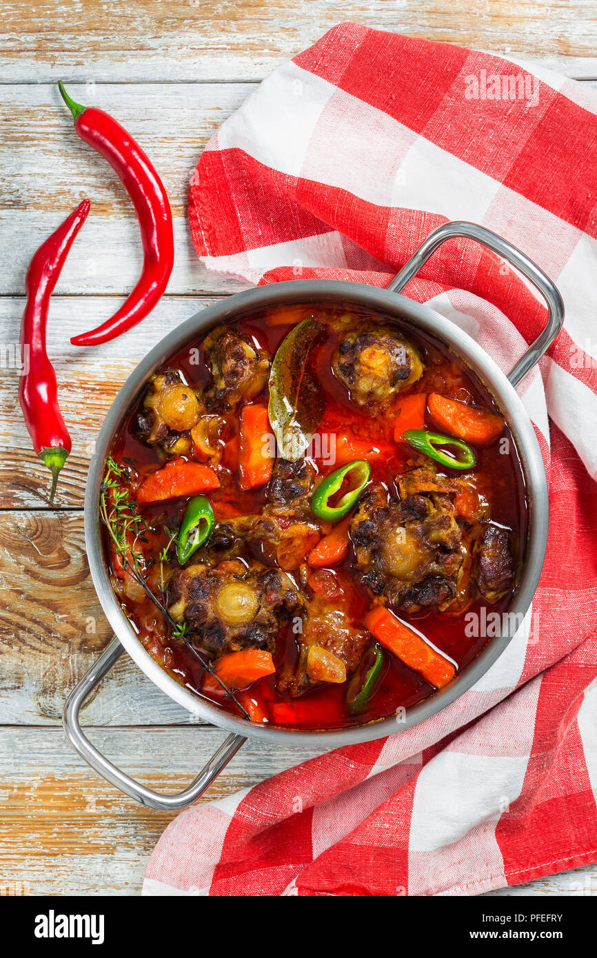 Rabo de Toro ou ragoût de boeuf en casserole avec le piment, l'ail et le thym. cuisine serviettes sur la vieille table en bois blanc, une cuisine traditionnelle de l'Espagne, au Banque D'Images