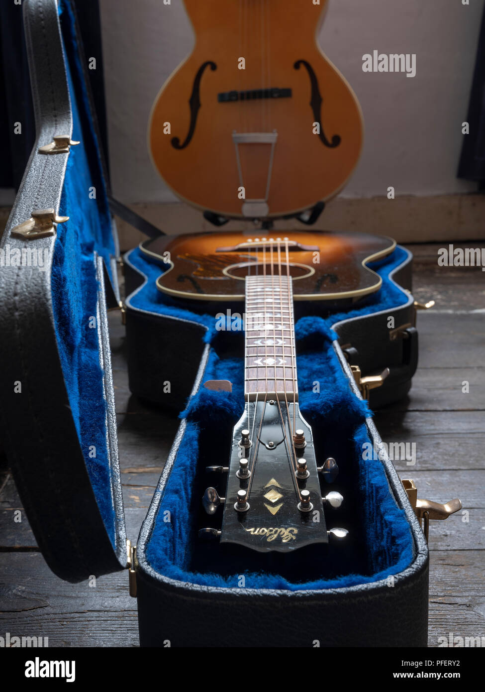 Guitare acoustique Gibson J-45 dans son cas avec une blonde archtop semi-acoustique Guitare f-trous à l'arrière-plan. Banque D'Images