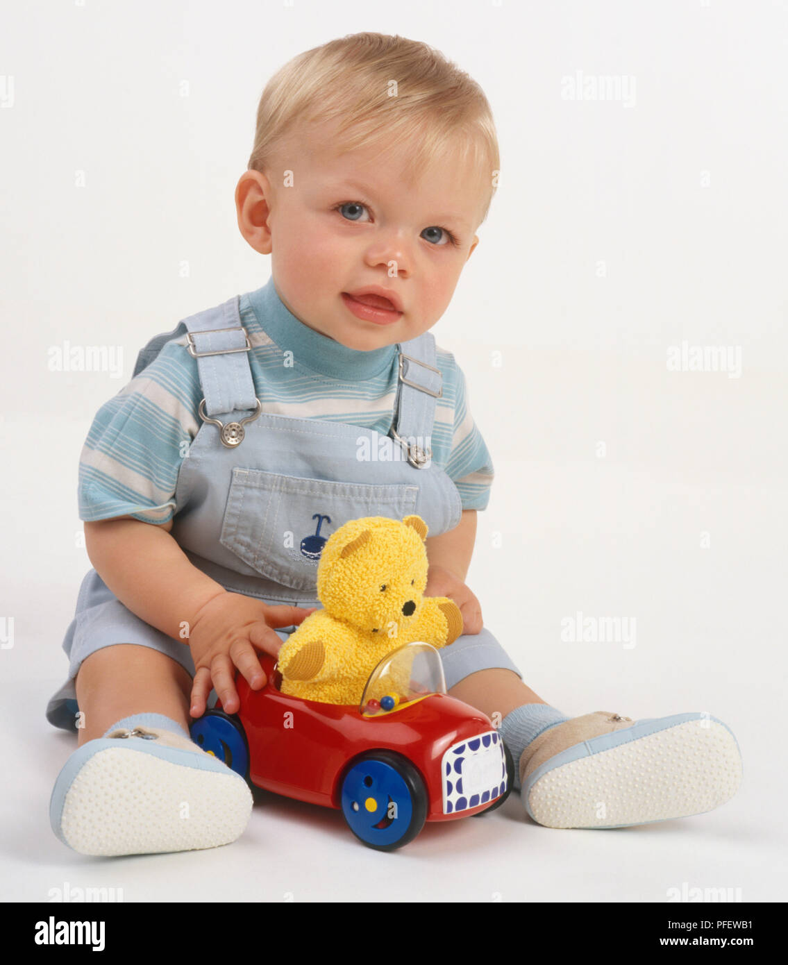 Bebe Garcon Aux Cheveux Blonds En Salopette Bleue Et Chemise Rayee Rouge Assis Avec Voiture Jouet En Plastique Jaune Avec Des Ours En Peluche A L Interieur Entre Les Jambes Jusqu A La Voiture