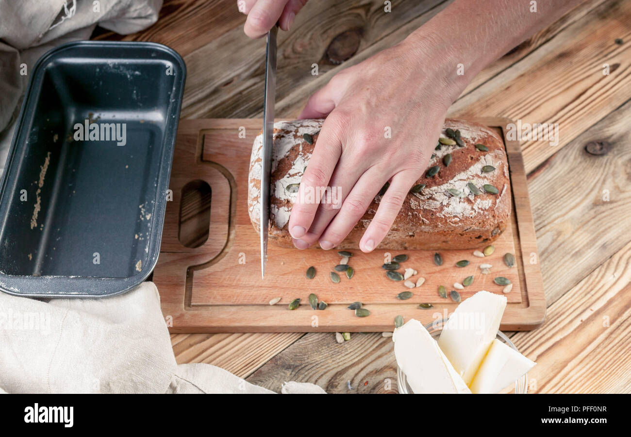 Couper les mains des femmes de pain de seigle fait maison sur une table en bois Banque D'Images