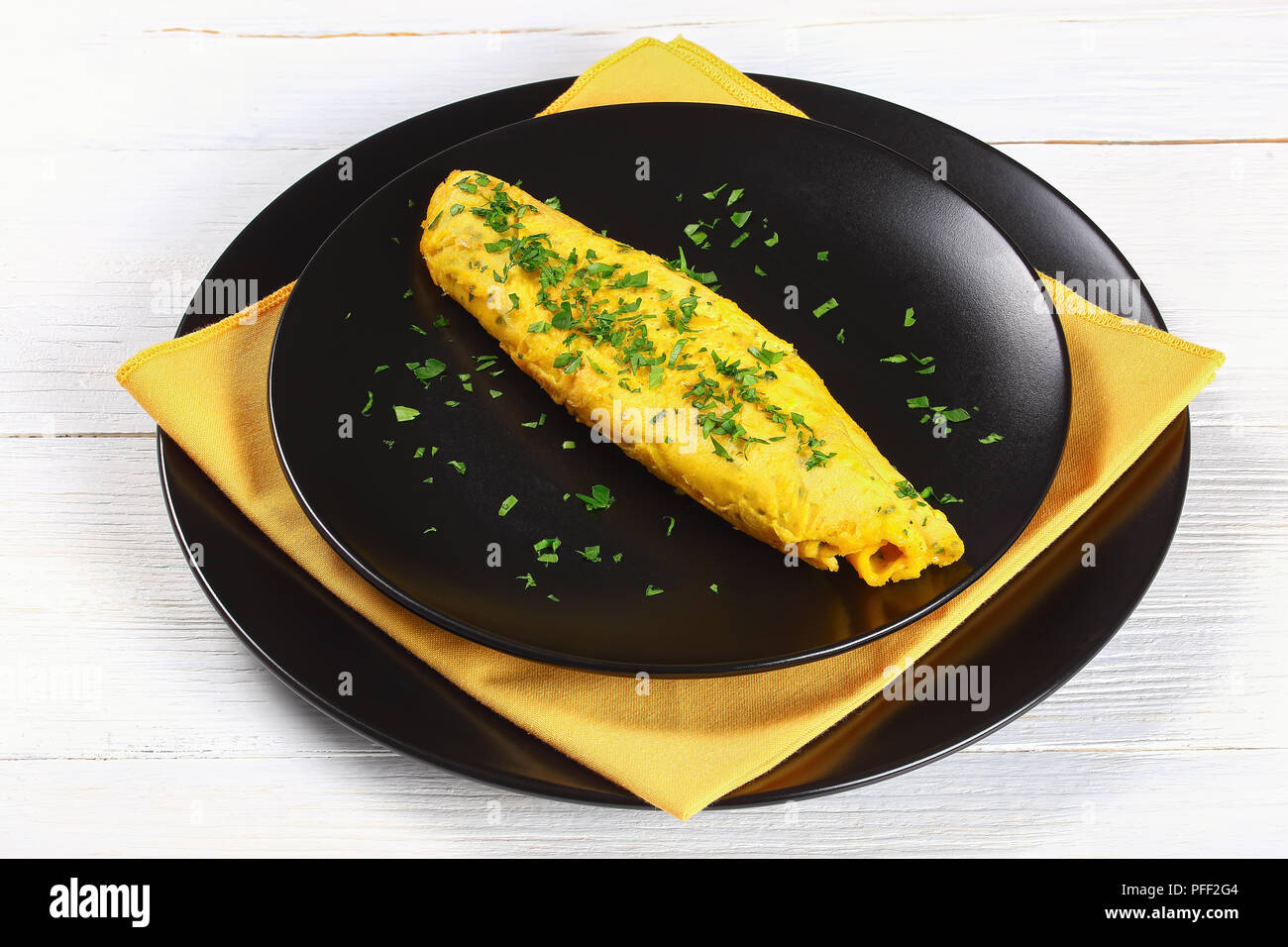 Français de base classique trois oeufs omelette moelleux parsemé de persil  haché sur les plaques noires avec serviette jaune, sur une table en bois  blanc, vue depuis l'ab Photo Stock - Alamy
