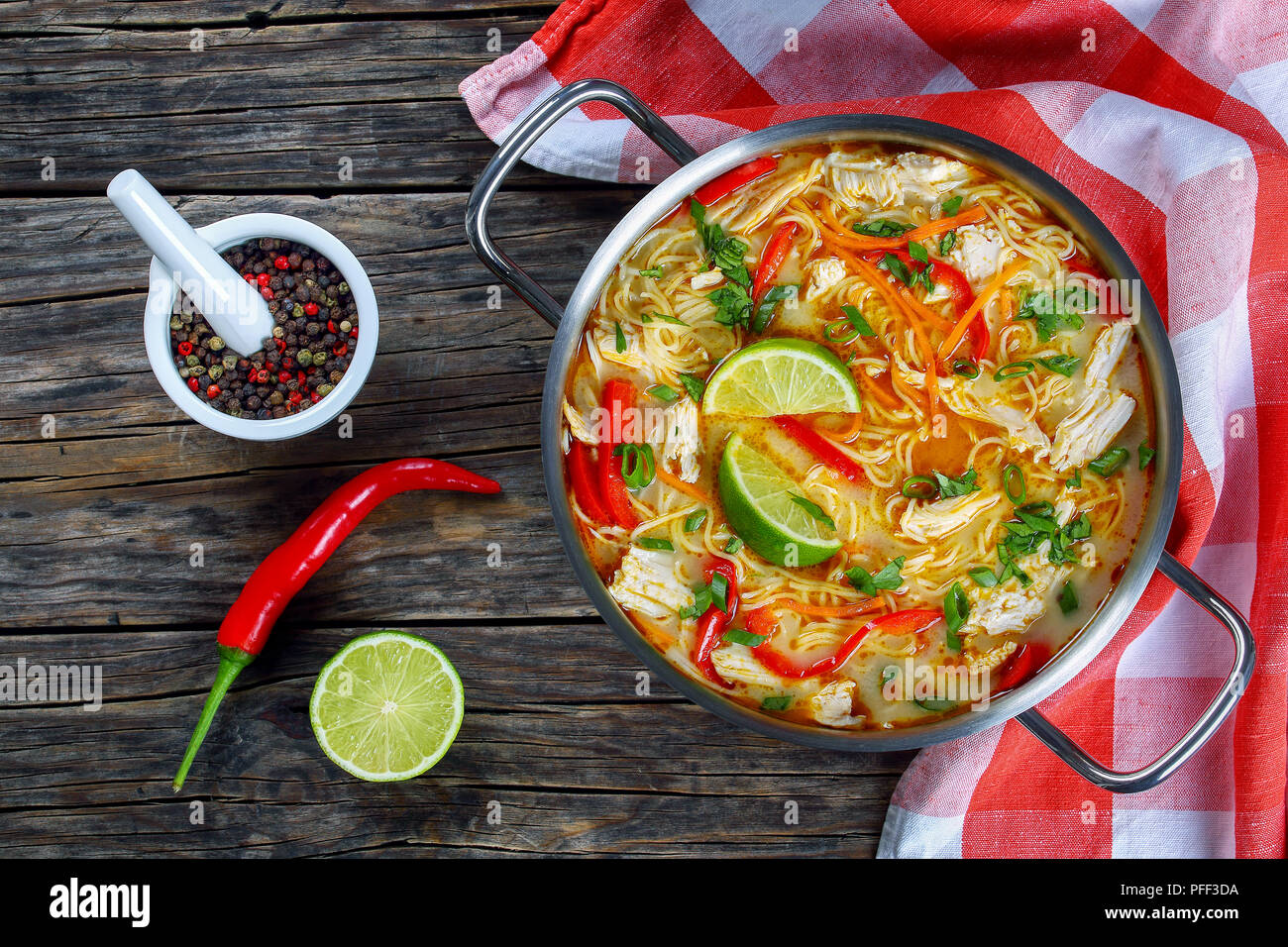 Délicieux et épicé de poulet thaï au curry vert soupe de nouilles en casserole sur la vieille table en bois foncé avec une serviette de cuisine traditionnelle, recette classique, vue Banque D'Images