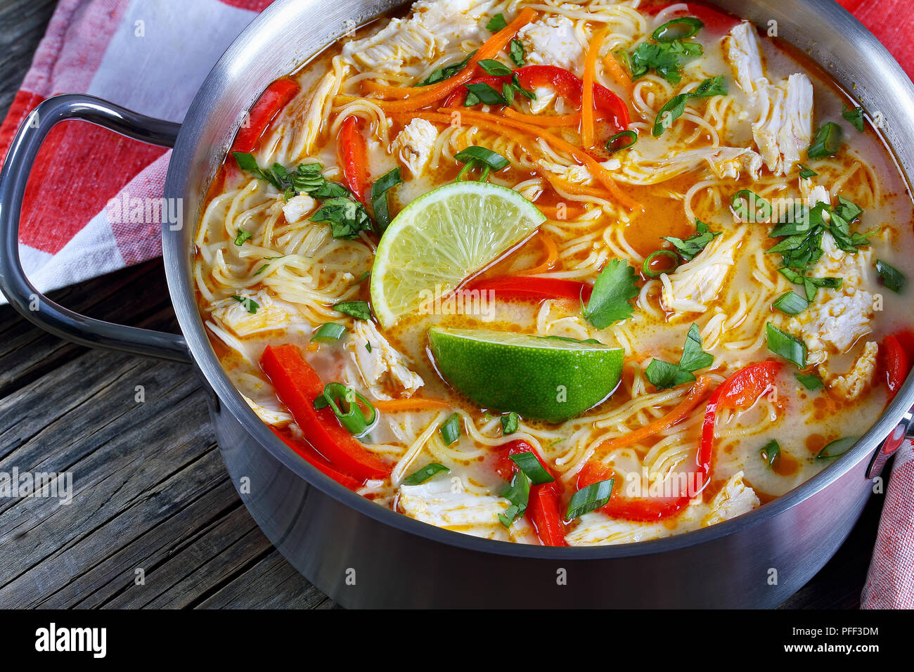 Close-up of delicious et poulet thaï au curry vert au lait de coco dans la casserole sur la vieille table en bois foncé avec des essuie-tout, la tra Banque D'Images