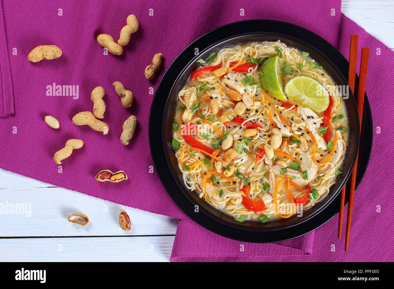 Yummy curry vert de poulet au lait de coco, l'oignon vert et la coriandre finement hachés dans un bol noir parsemé de graines de sésame et d'arachide Banque D'Images