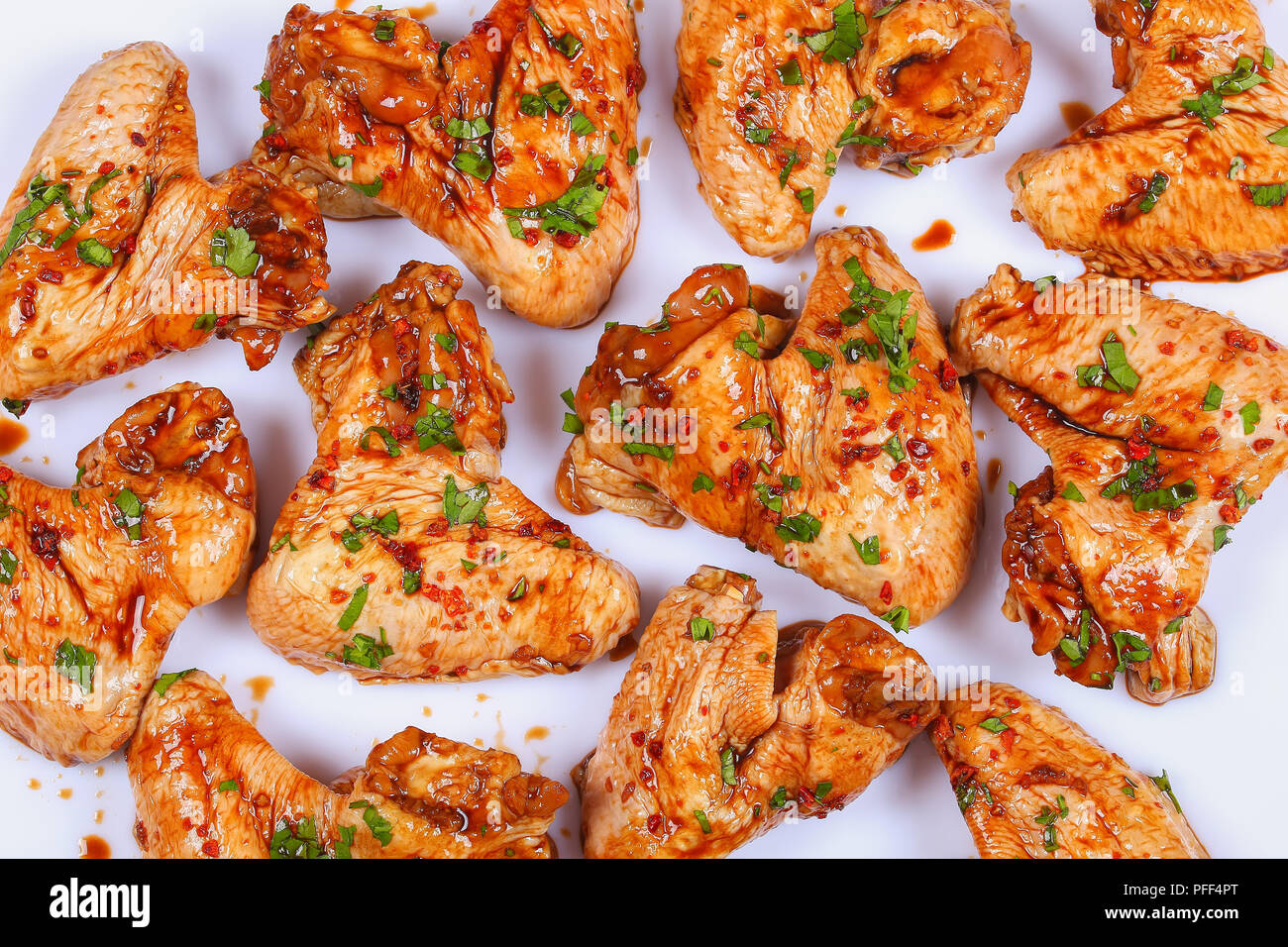 Les ailes de poulet marinées au jus de miel, sauce soja, épices et  saupoudrés de persil finement haché sur fond blanc, préparé pour rôtir, asi  Photo Stock - Alamy