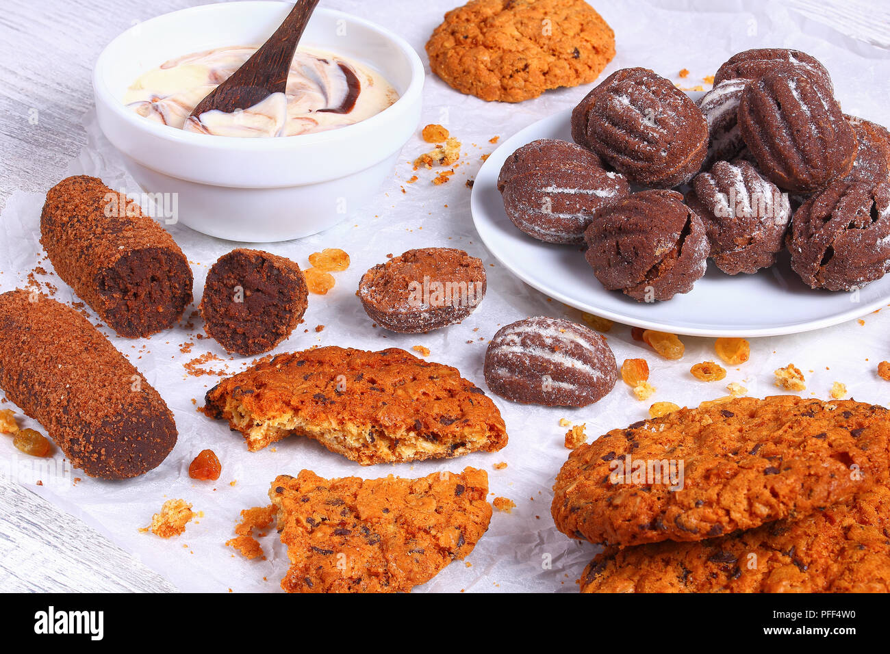 Biscuits au chocolat maison, des raisins secs, noix et chocolat cookies yaourt frais dans un bol sur le papier sur la table en bois, vue de dessus, à proximité- Banque D'Images