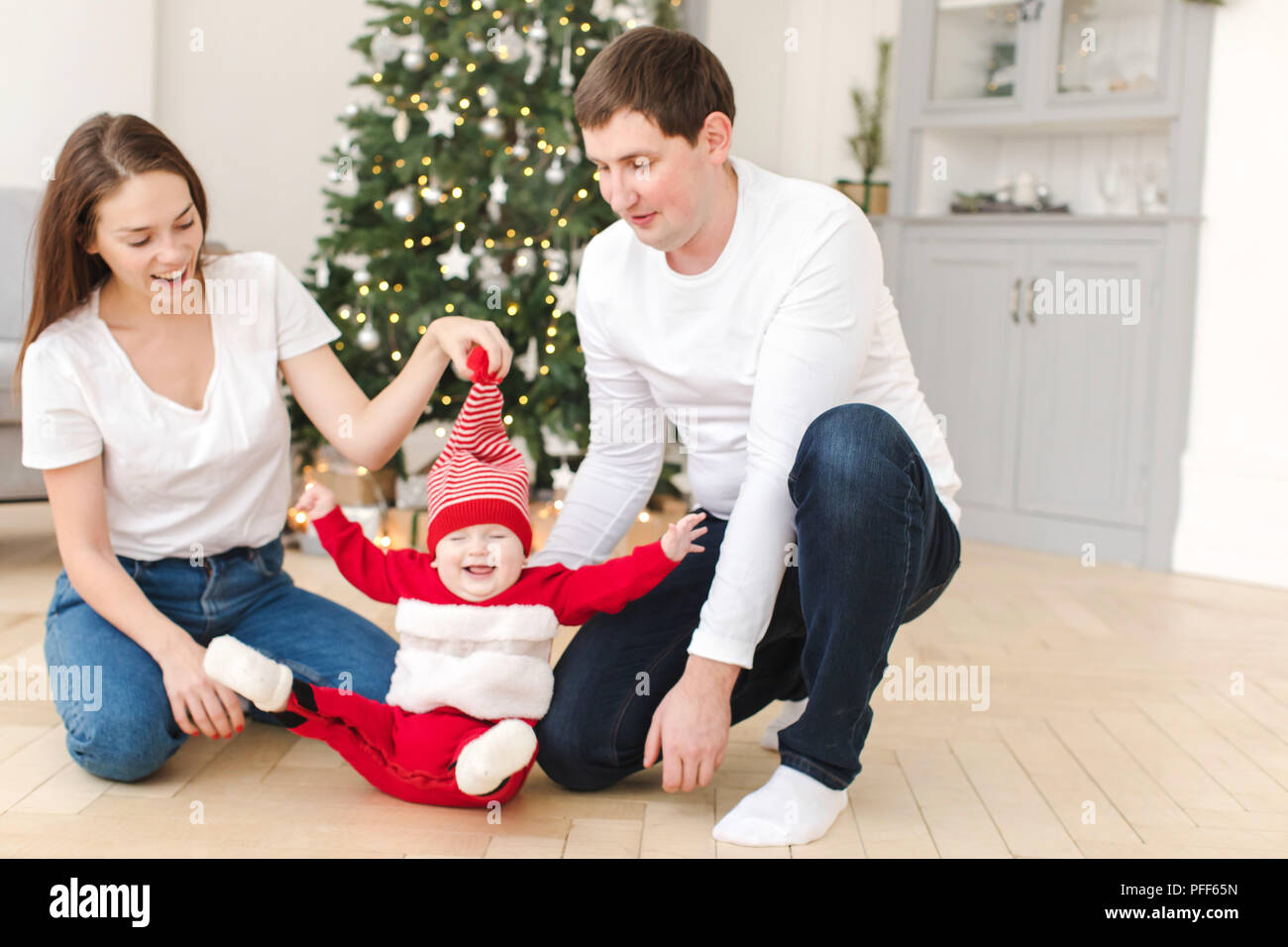 Les parents de jouer avec bébé près de l'arbre de Noël Banque D'Images