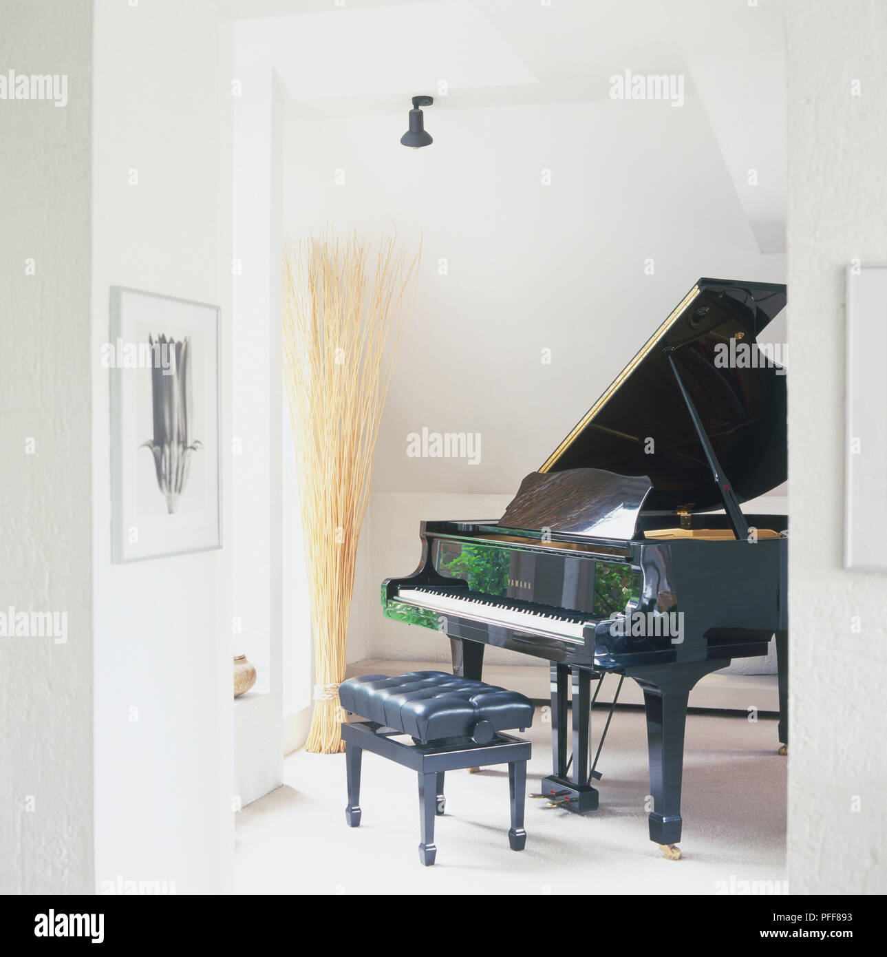 Grand piano avec tabouret rembourré en coin de chambre mansardée. Banque D'Images
