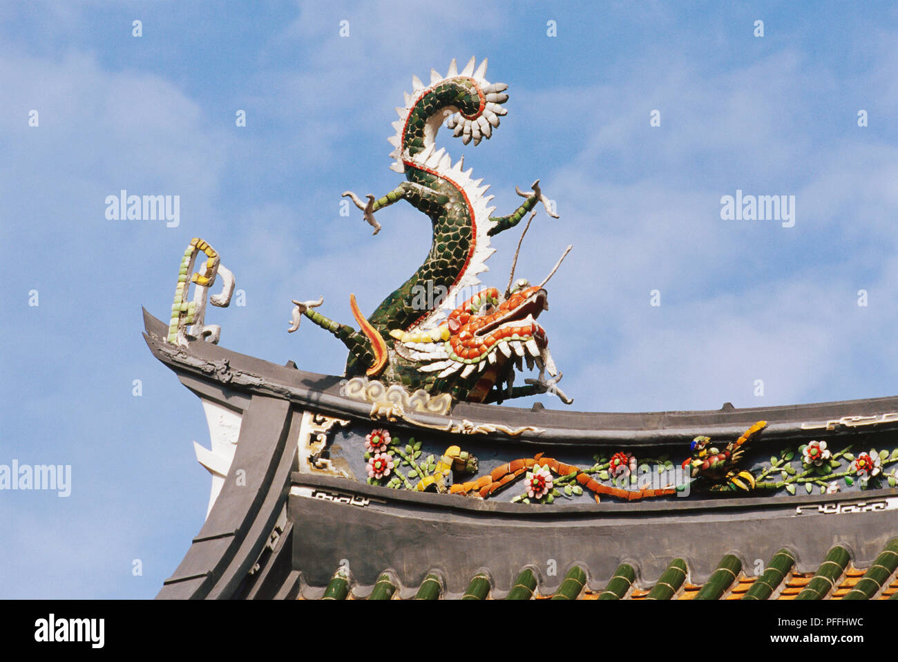 Singapour, Temple Thian Hock Keng, un des Dragons jumeaux toit décoration, vert, jaune et rouge dragon qui repose sur les principes du yin et du yang, curling queue dans l'air, les orteils de pieds évasés. Banque D'Images